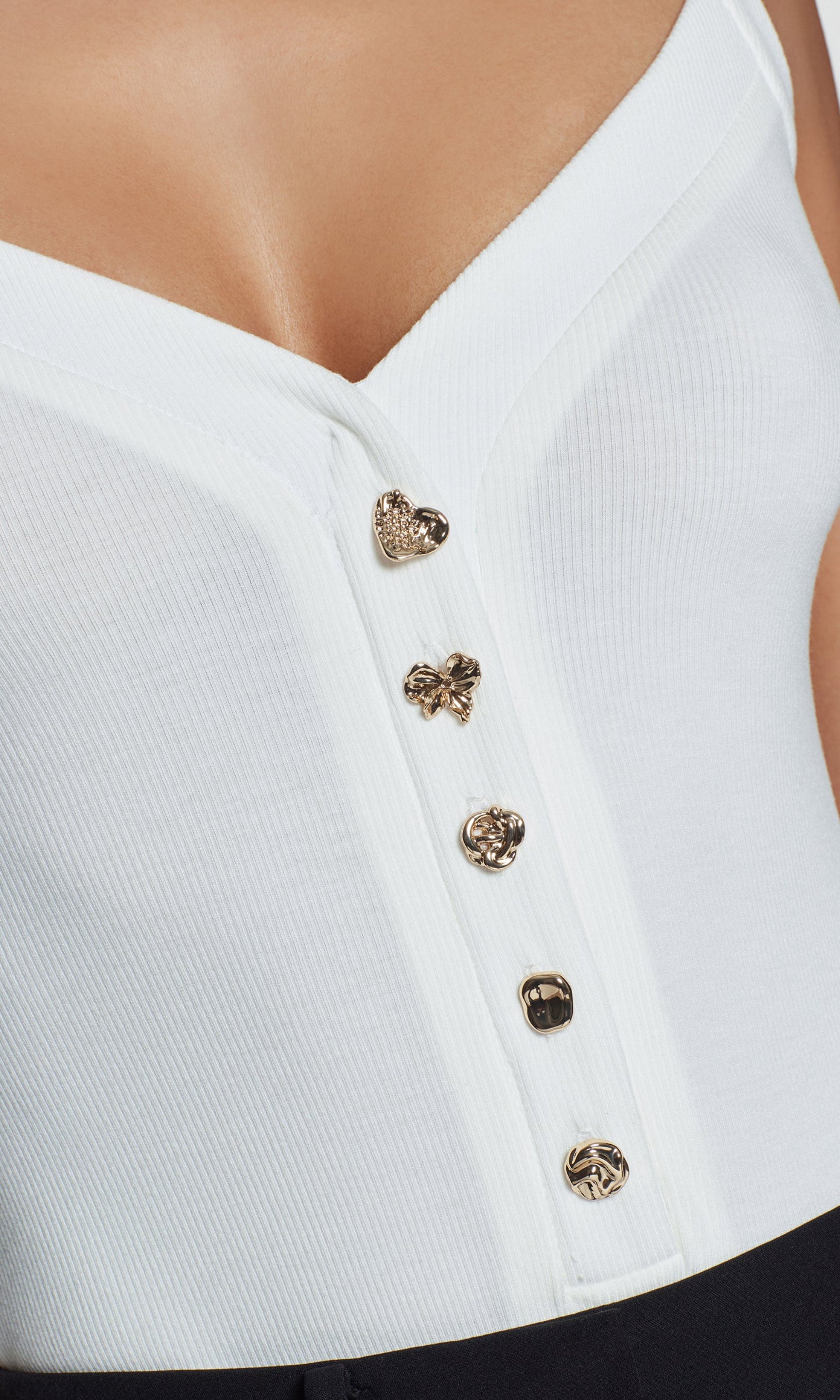 Close-up of white top with decorative buttons on a plain background
