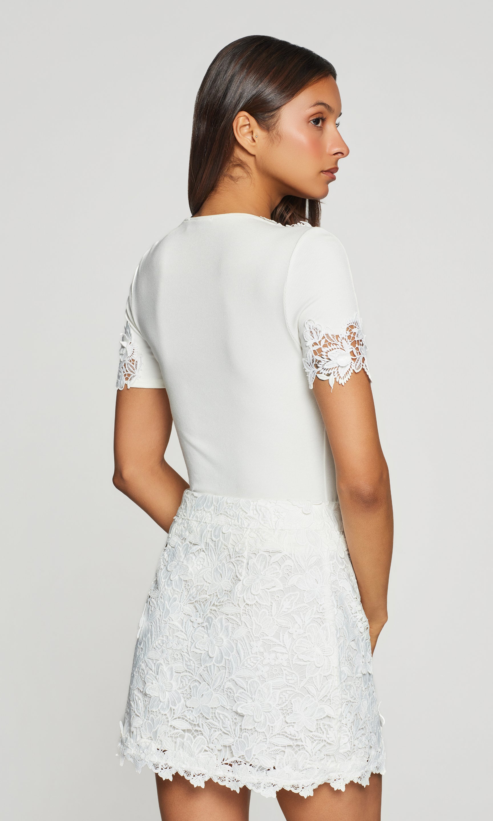 In a rear view, the model wears the Shiloh 3D Lace Combo Top in white, showing the clean back and lace-trim short sleeves.