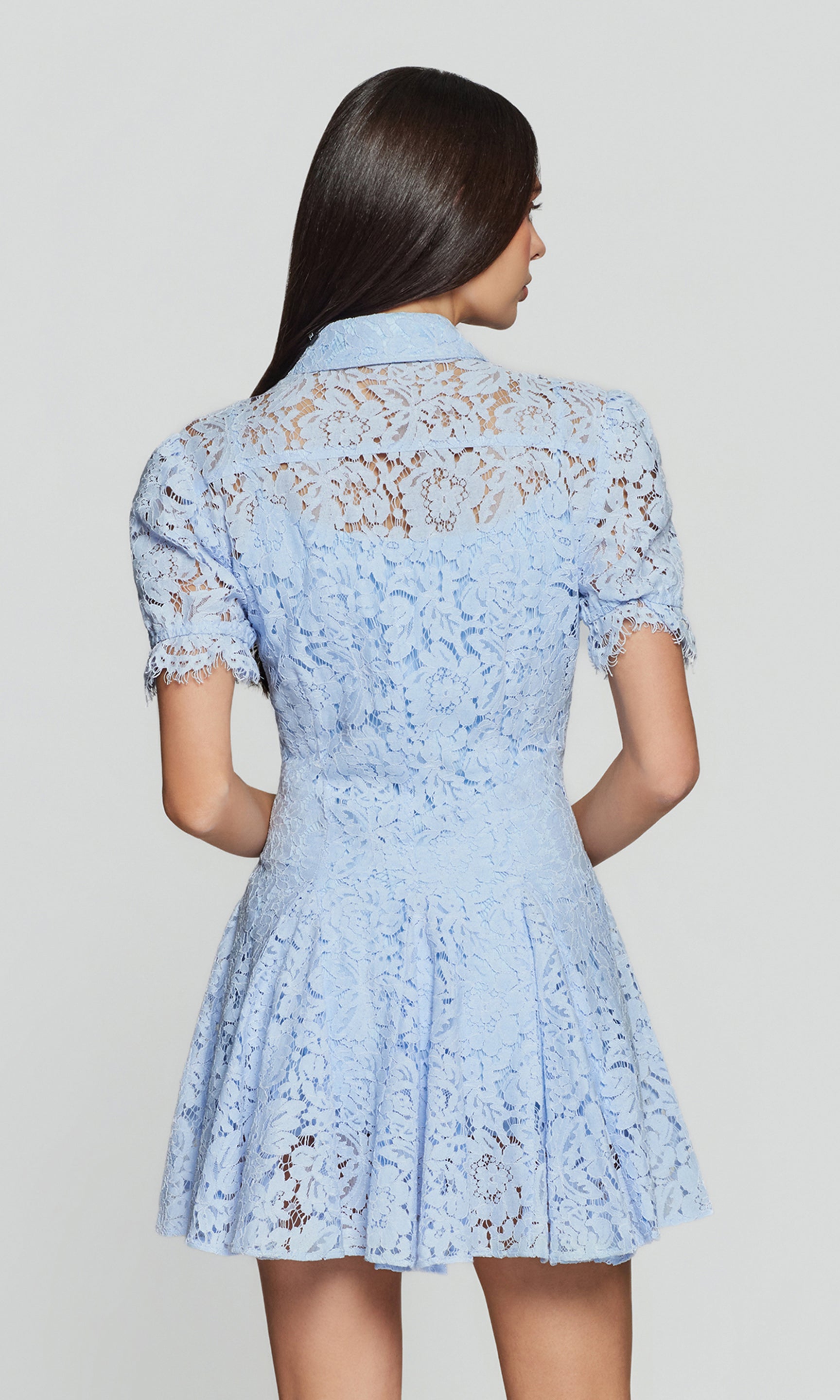 Back view of light blue lace dress worn by a person on a plain background