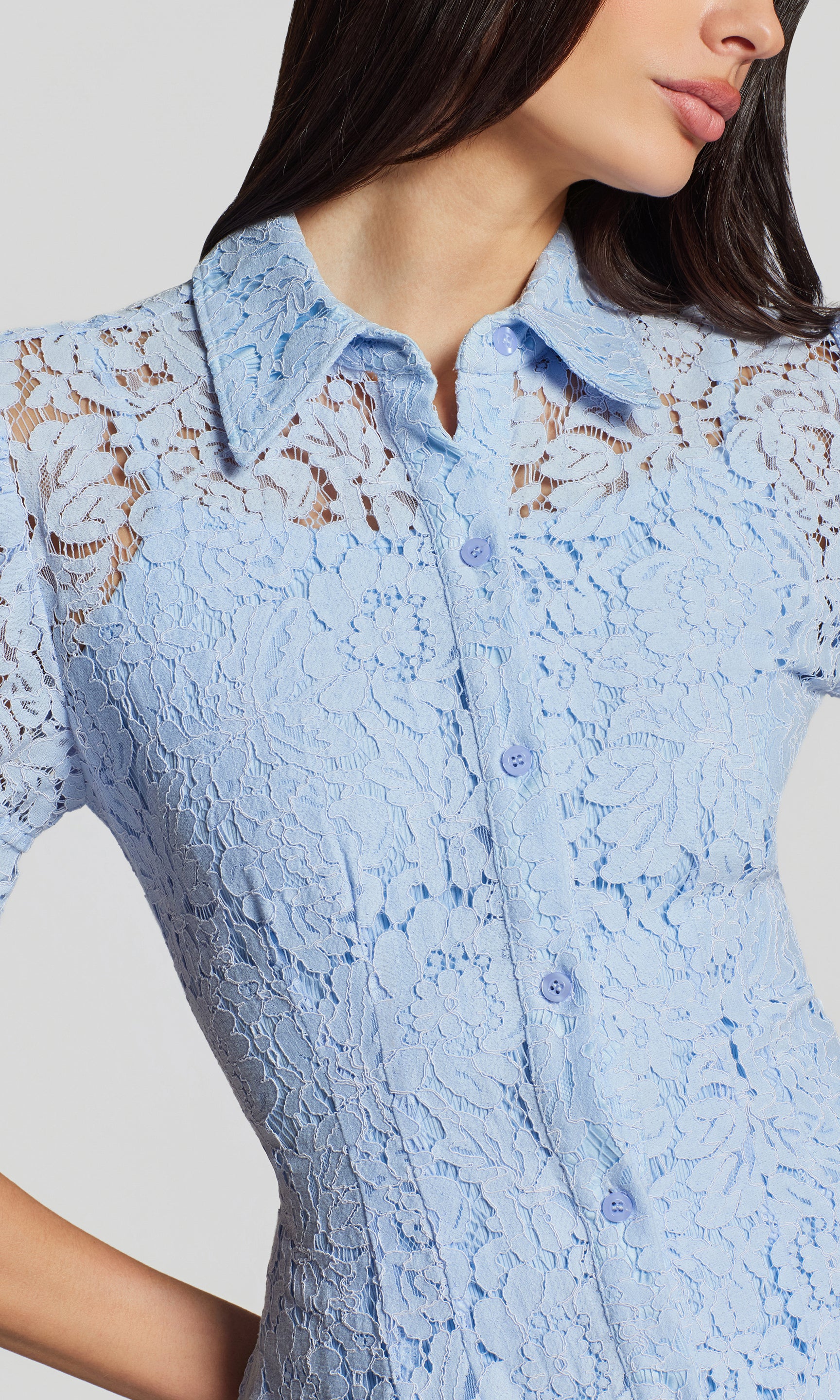 Close-up of light blue lace dress worn by a model against a neutral background