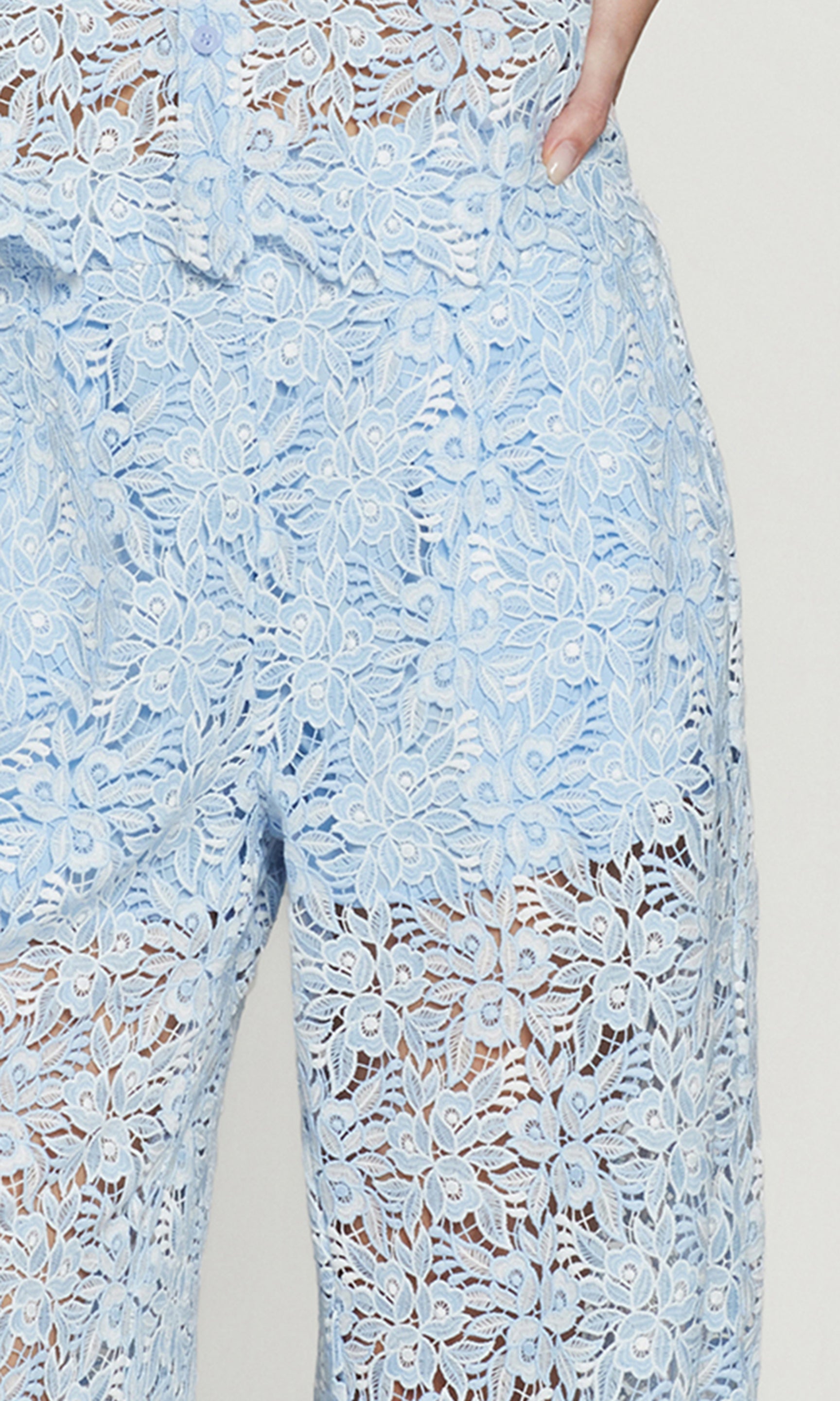 Close-up of light blue lace pants on a plain background