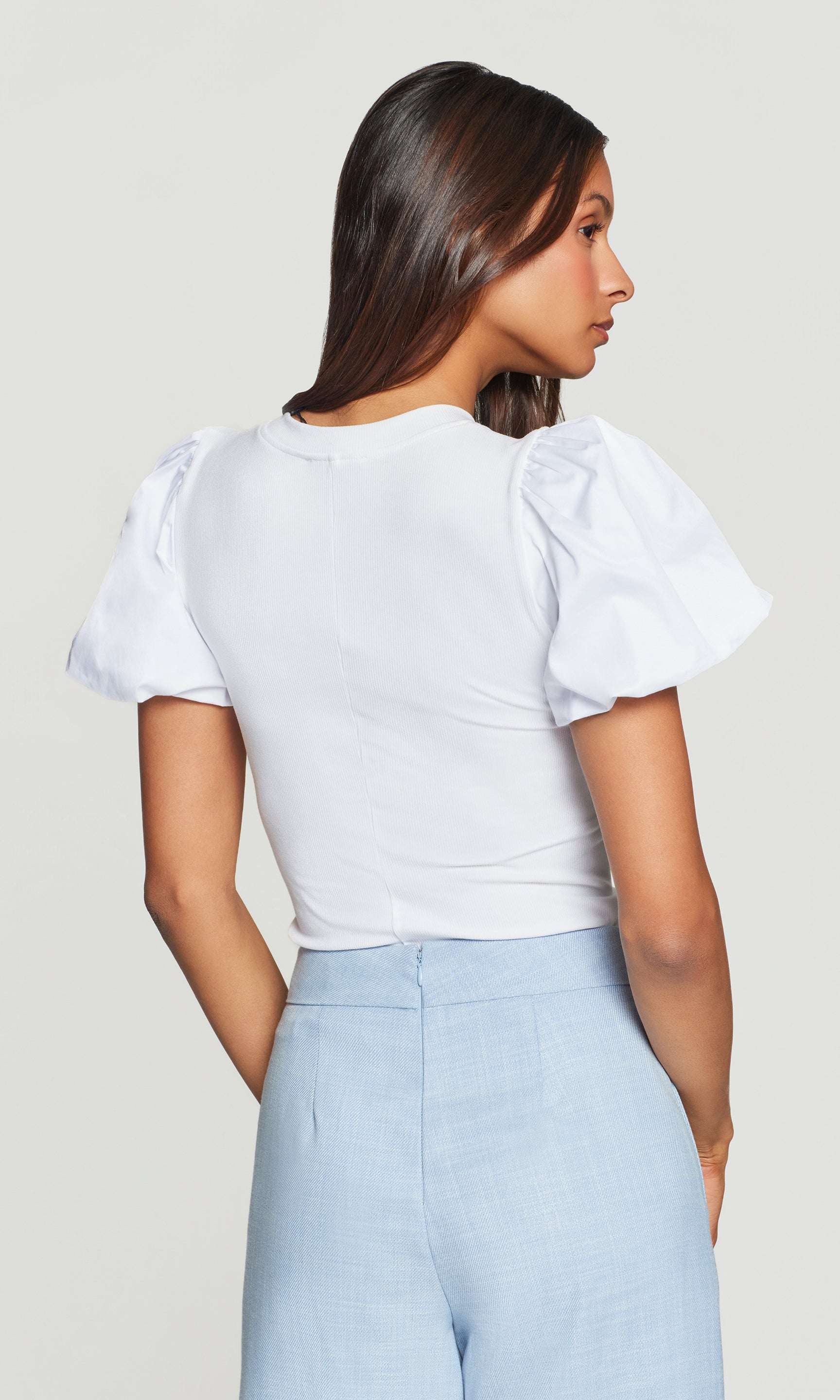 In a rear view, the model wears the Teigan Poplin Combo Top in white, showcasing the structured puff sleeves and clean back silhouette.