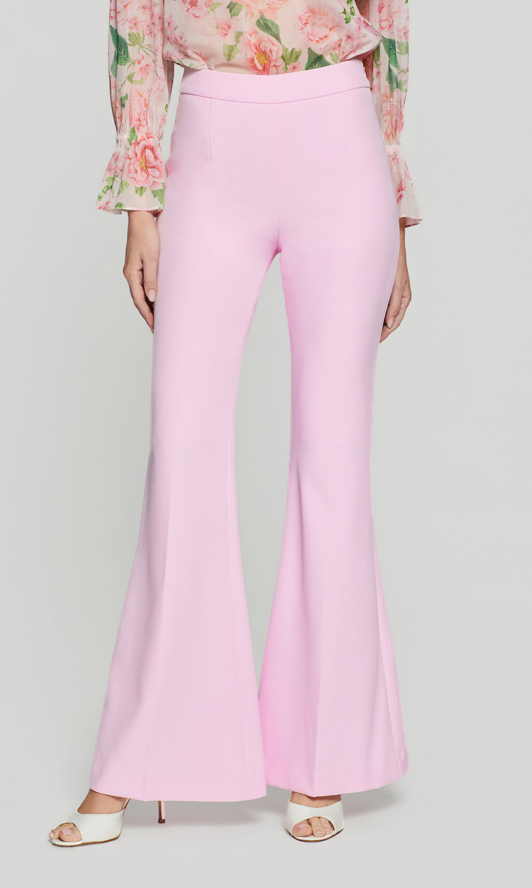 Pink flared pants worn by a person on a light gray background