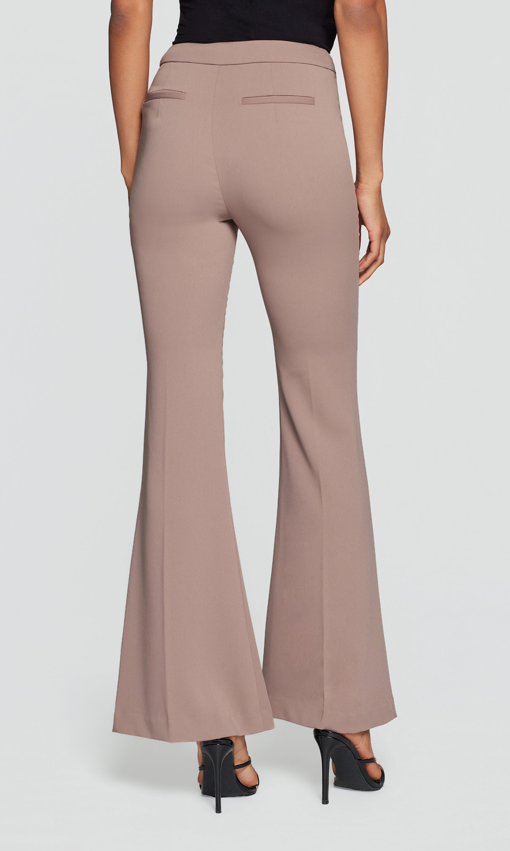 Model wears the taupe Wesley Crepe Pants in a studio back view, showing the fit through the hips and flared hem.