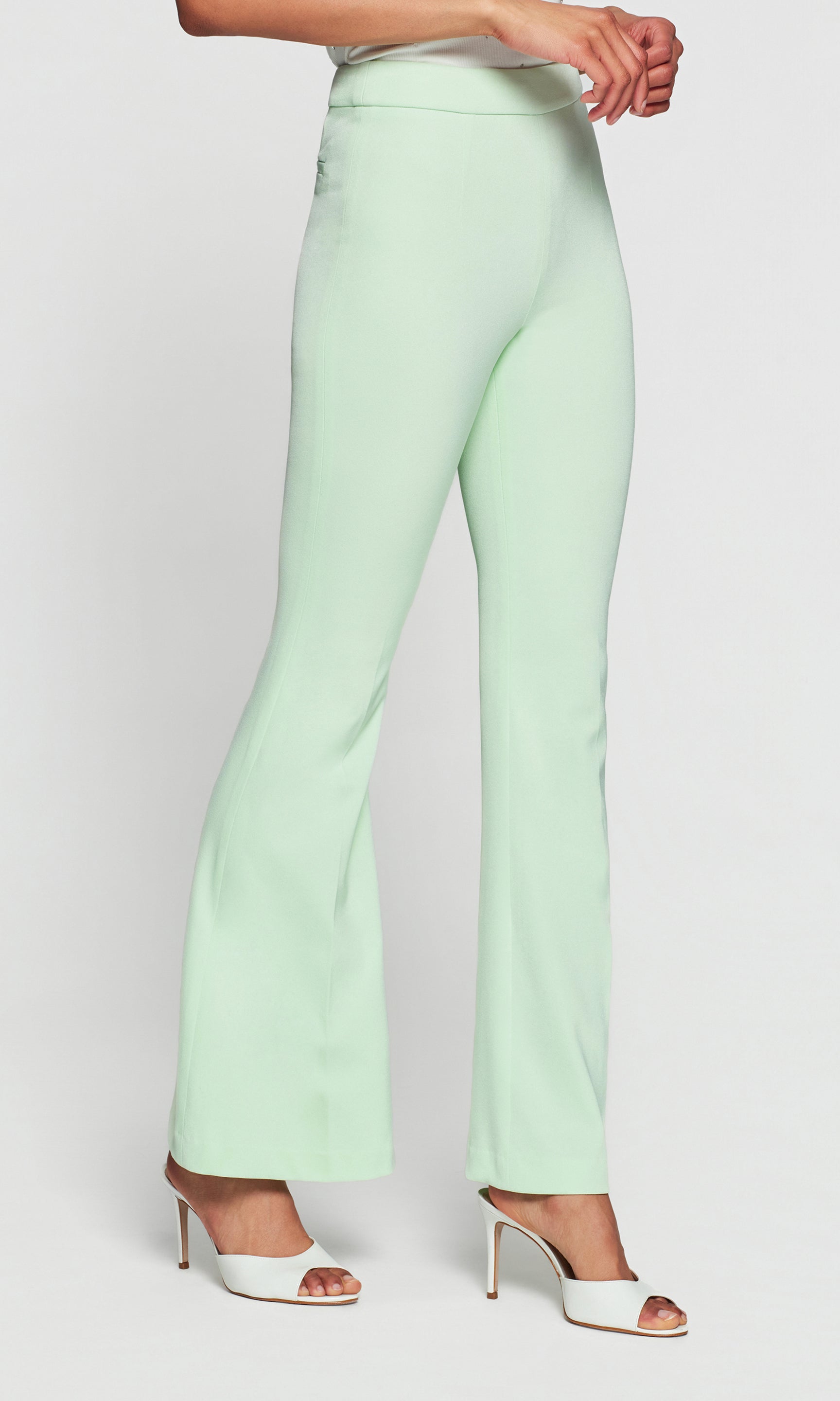 Model wears the Wesley Lightweight Crepe Pants in mint, full body lifestyle view styled with heels, showing how the tailored flare drapes perfectly over the shoe.