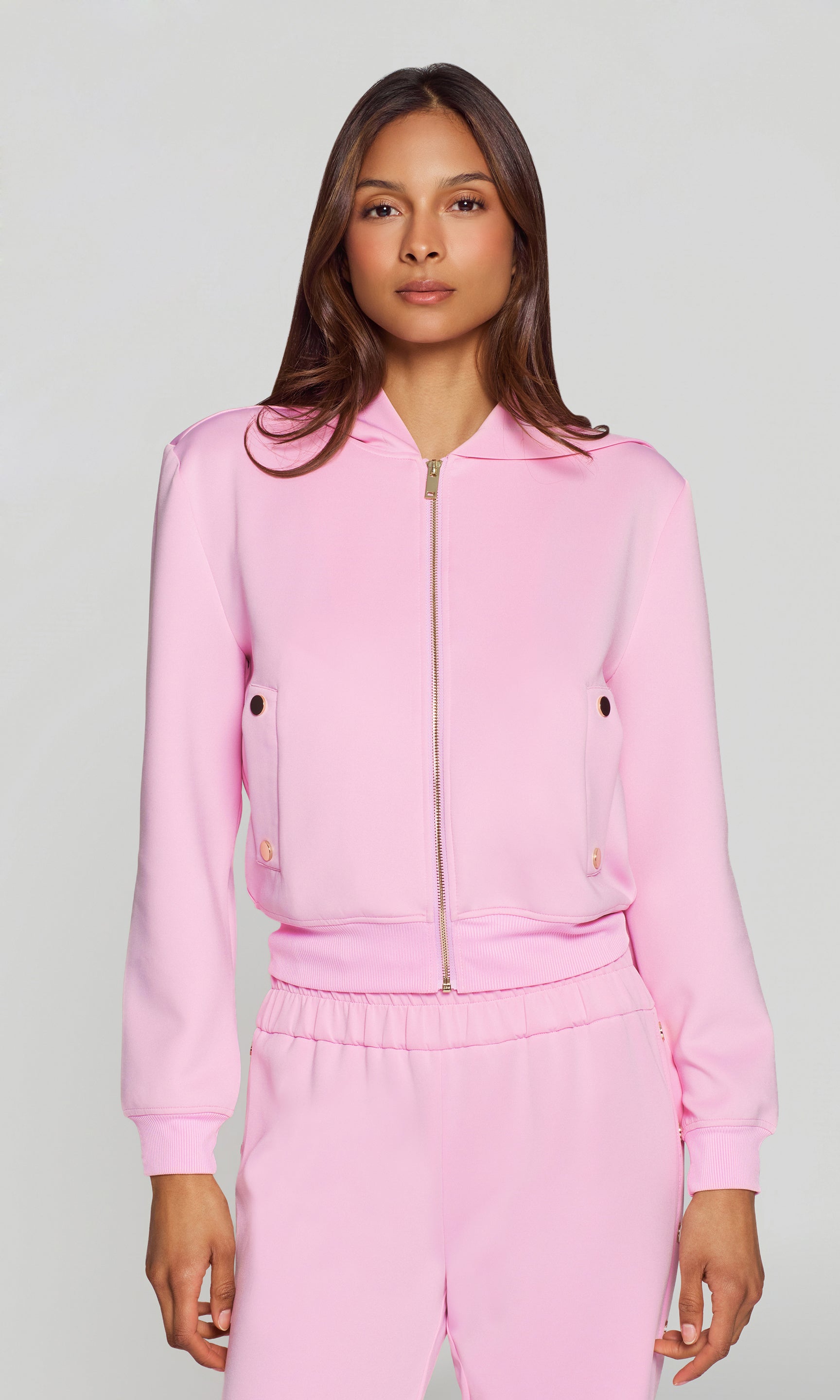 Woman wearing a pink tracksuit against a plain background