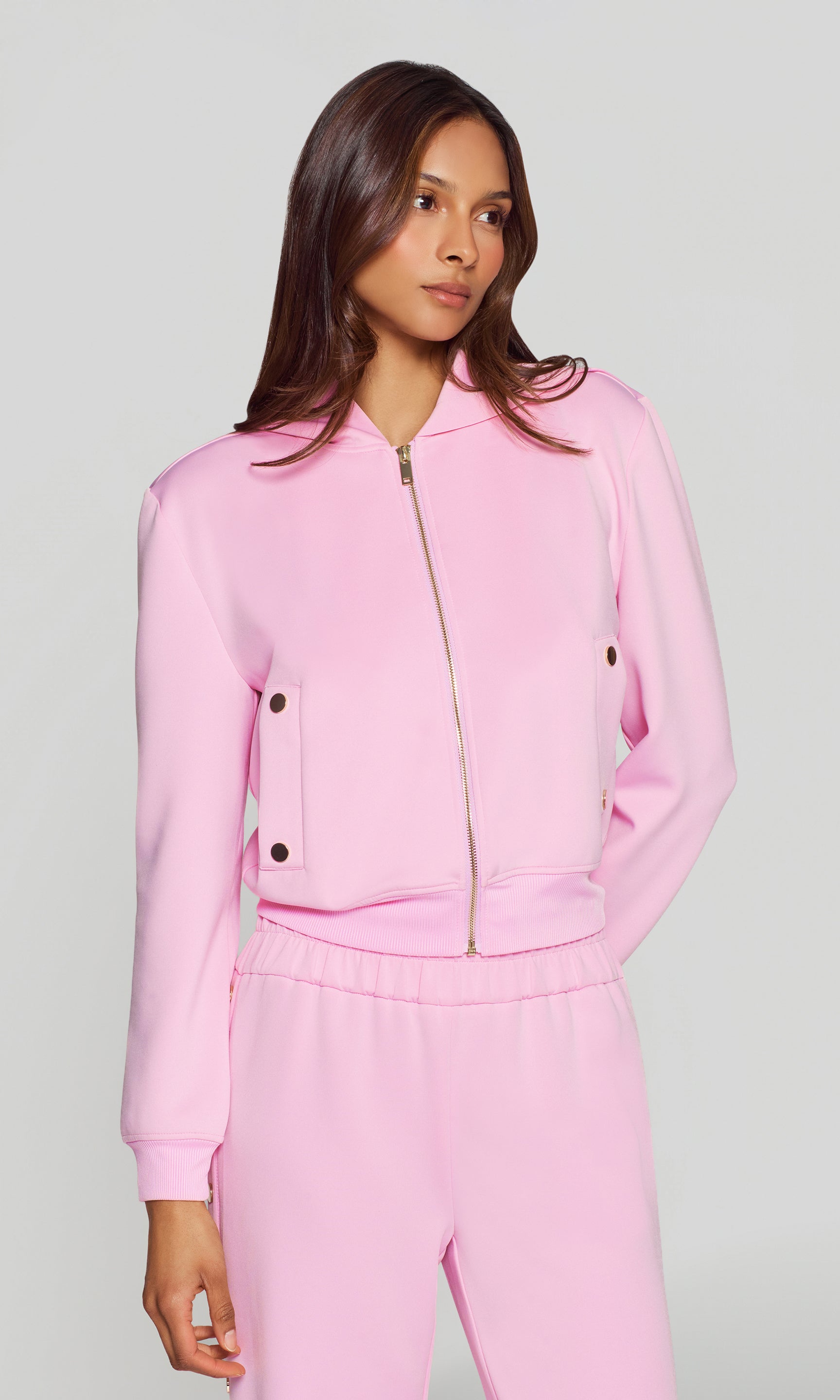 Woman wearing a pink tracksuit against a gray background