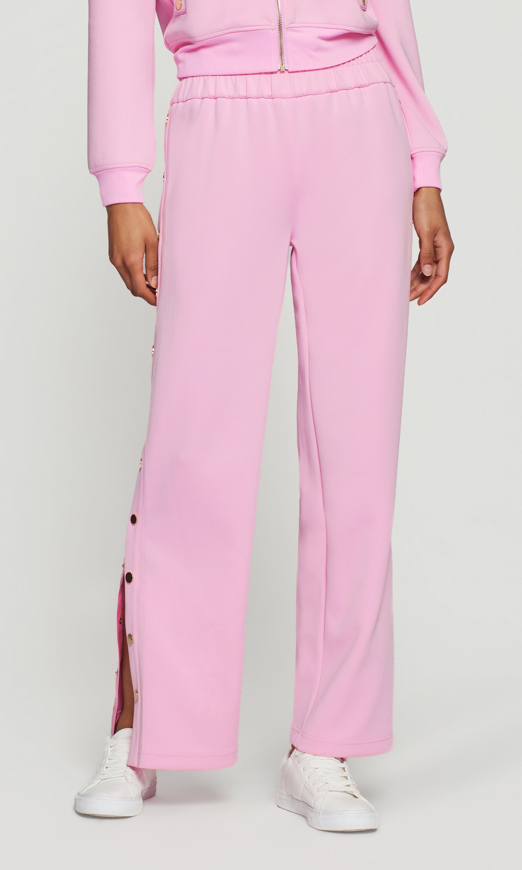Person wearing a pink outfit with high-waisted pants and a matching top on a white background