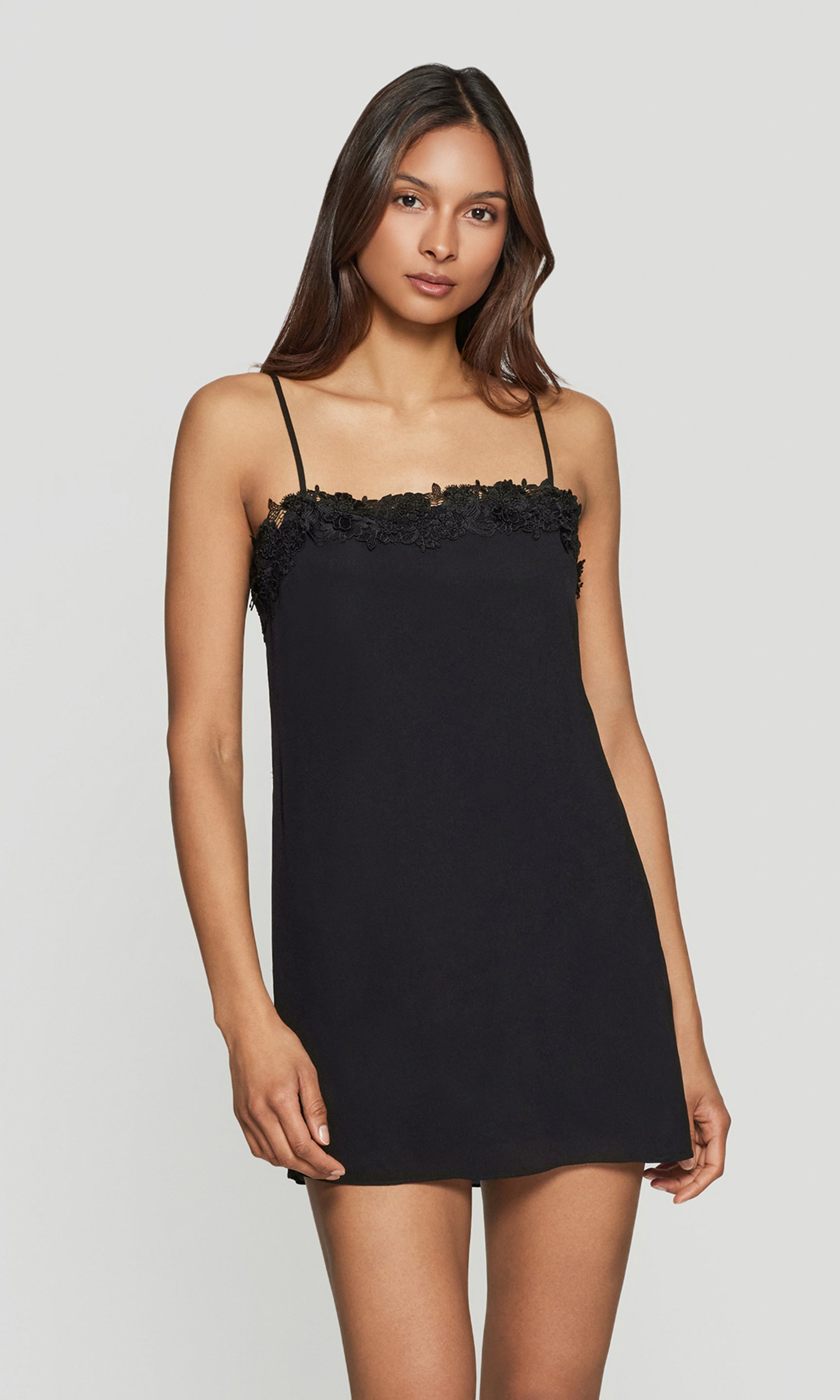 Woman wearing a black slip dress with floral details on a white background