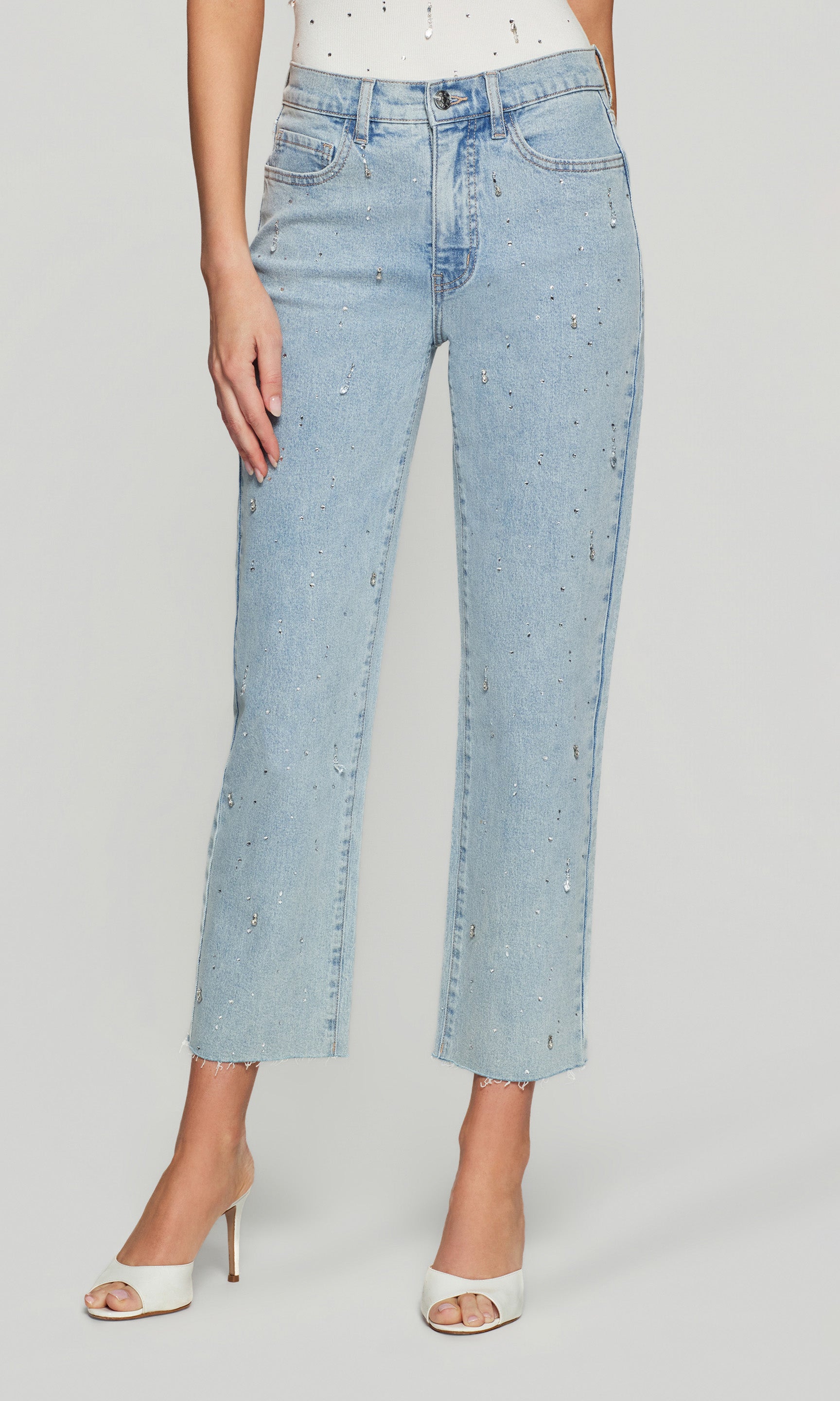 Light blue jeans with crystal embellishments worn by a person on a plain background