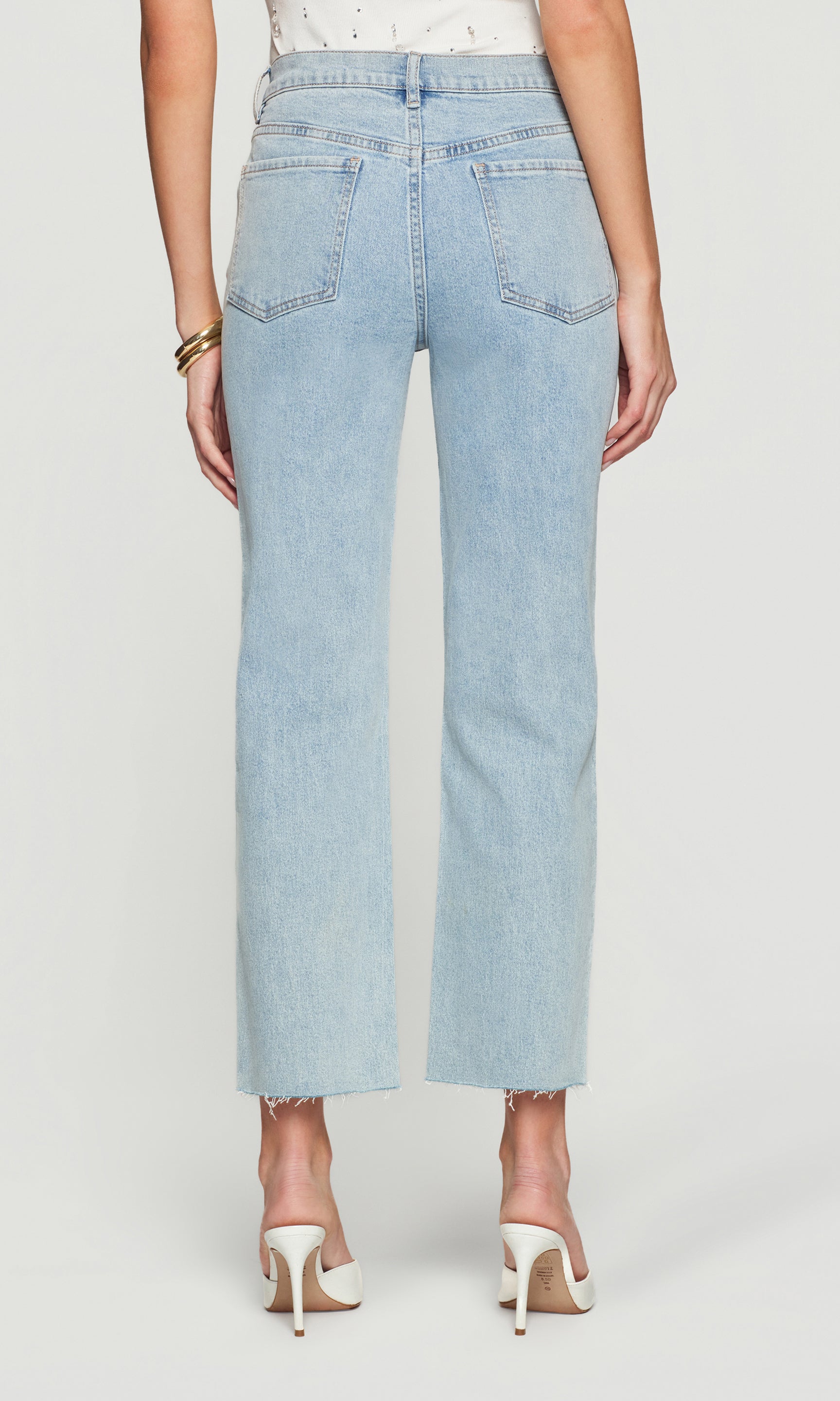 Back view of light blue jeans worn by a person on a white background