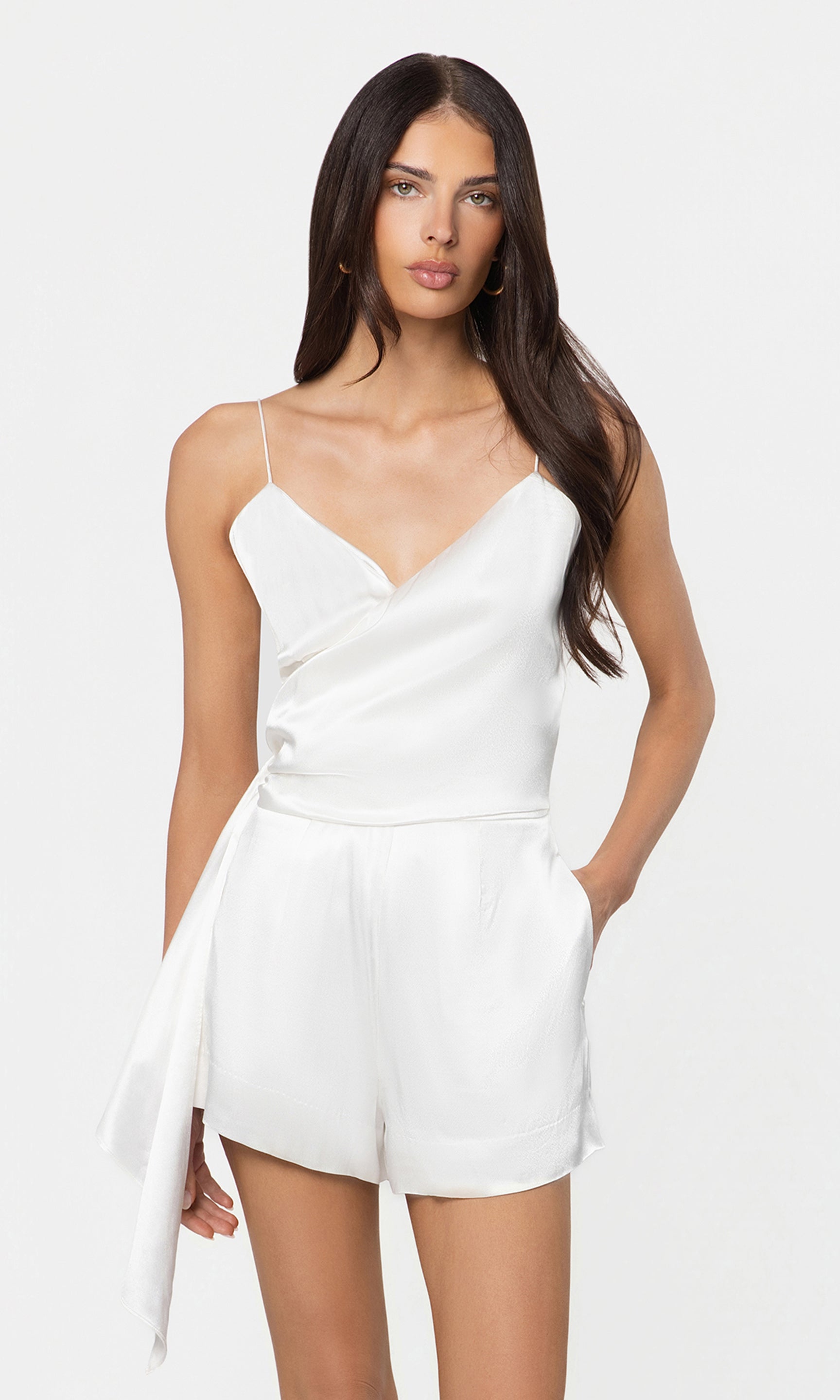 Woman wearing a white romper against a plain background
