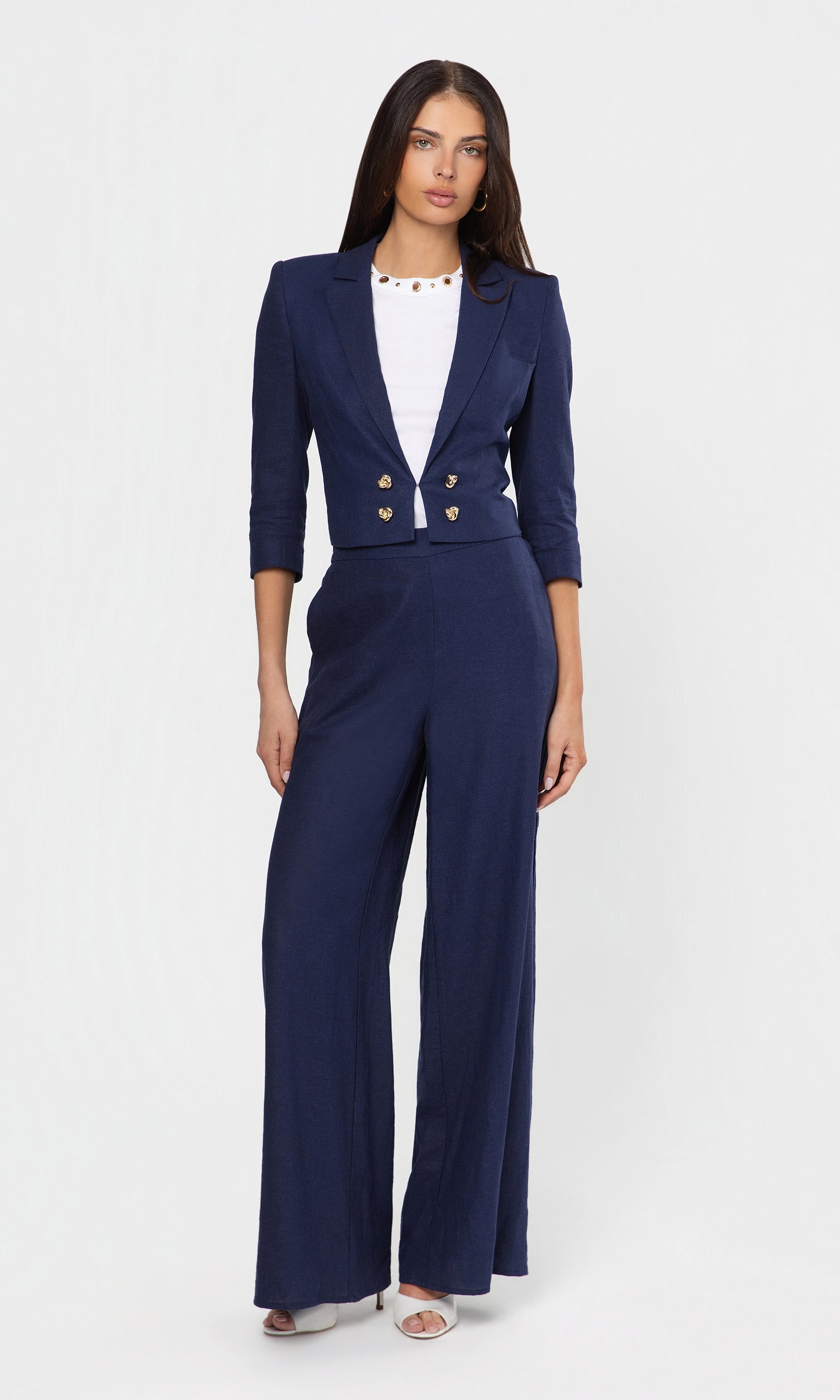 Woman wearing a navy blue suit with a white top on a light gray background