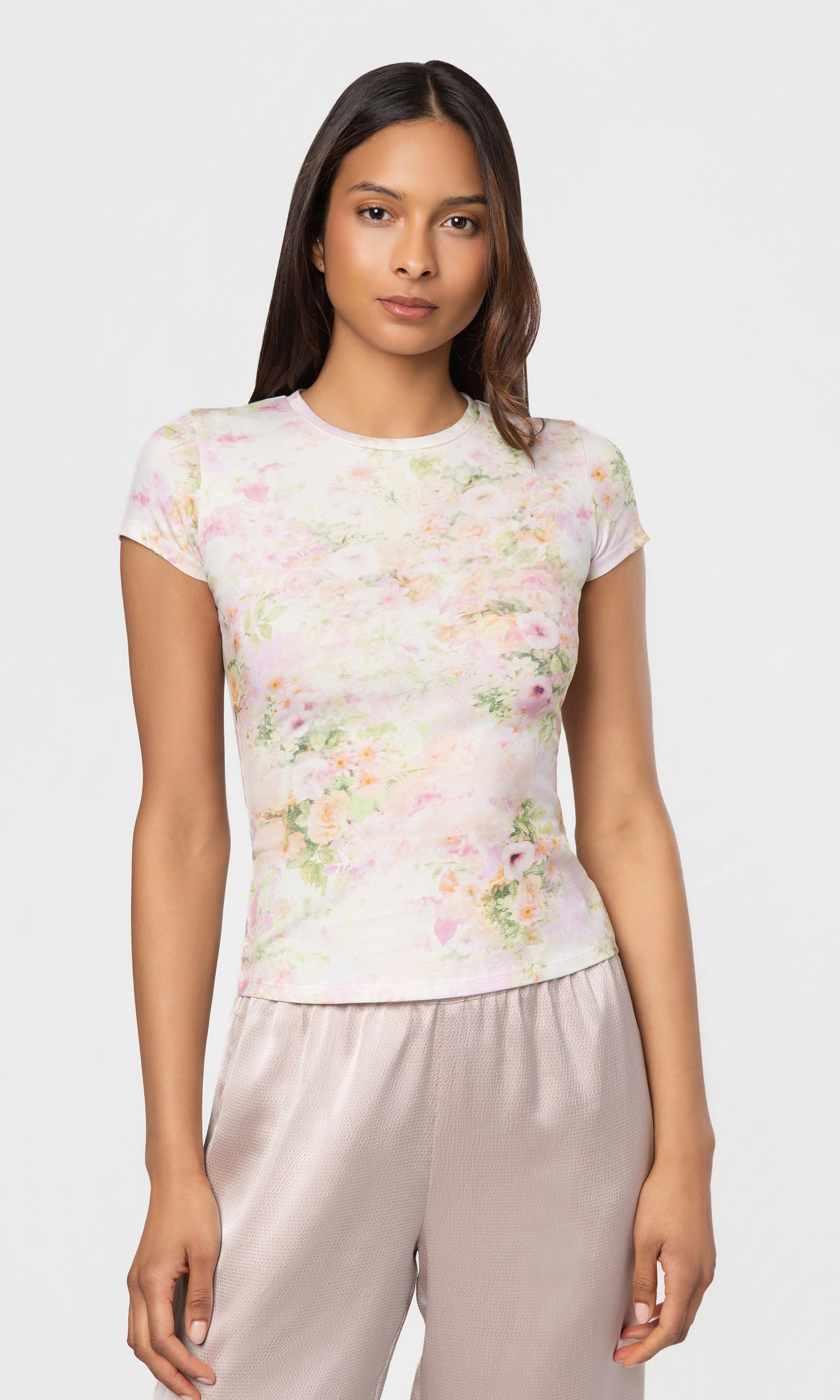 Woman wearing a floral top and light pants on a white background