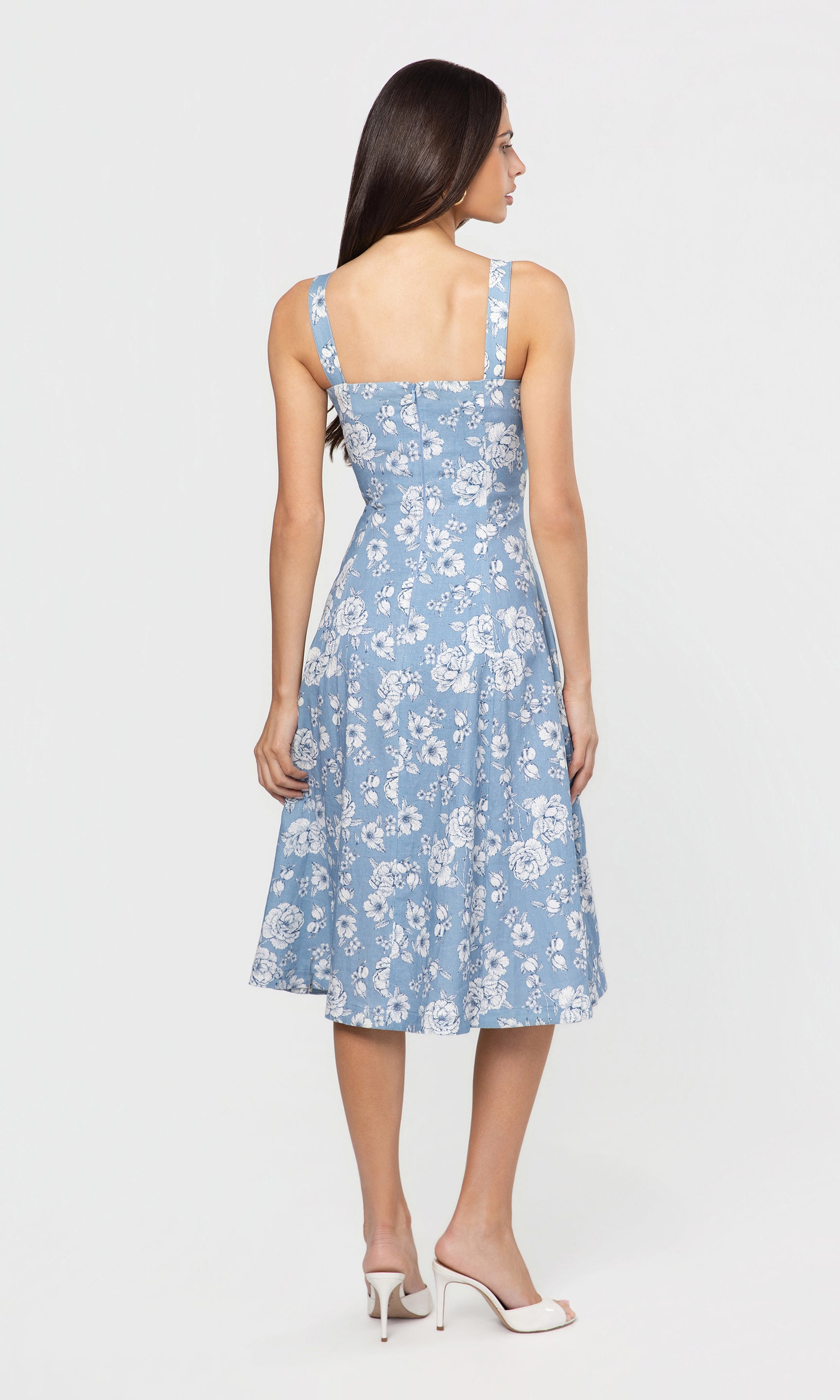 Back view of woman wearing a blue floral dress on a white background