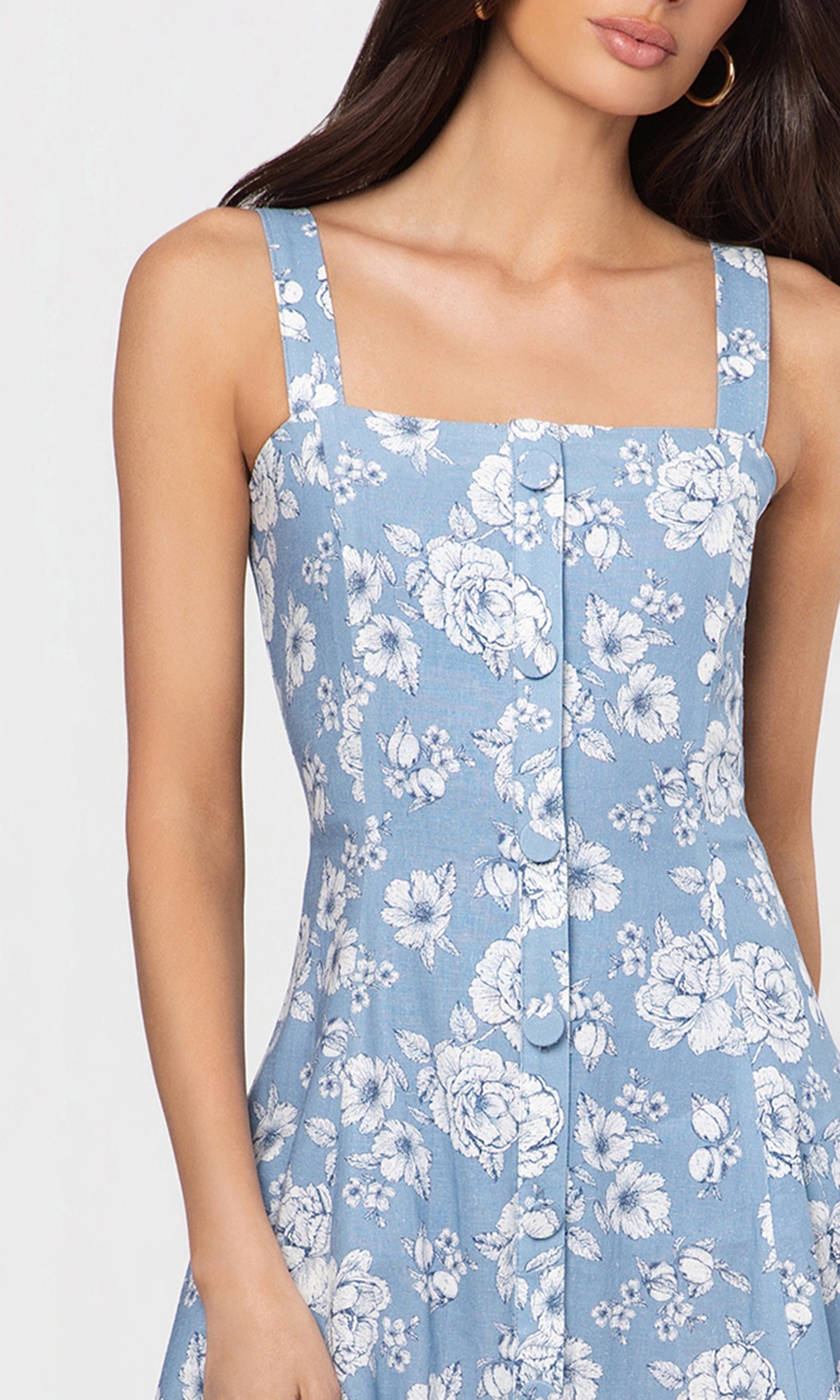 Close-up of woman wearing a blue floral dress against a white background