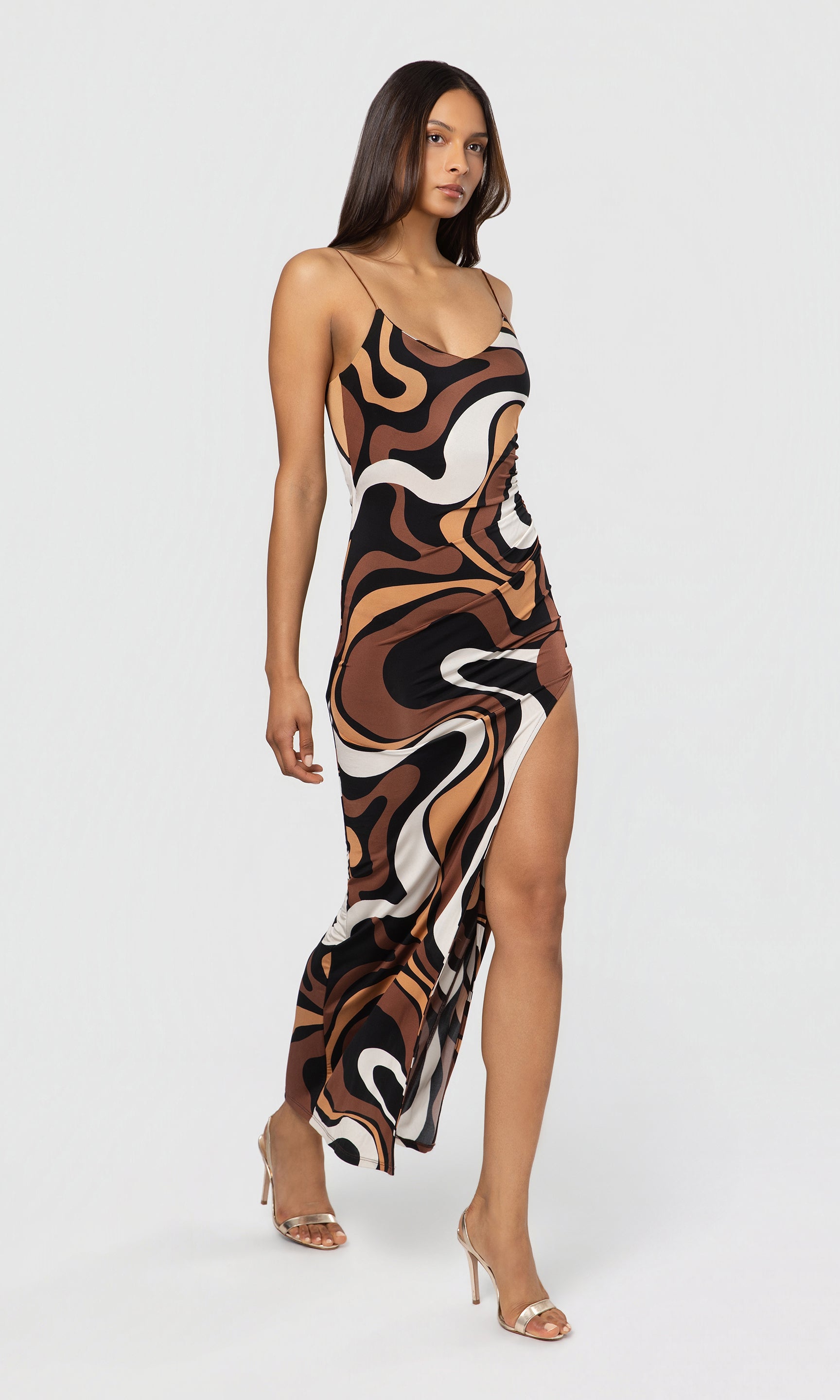 Side view of woman wearing a patterned slip dress on a white background