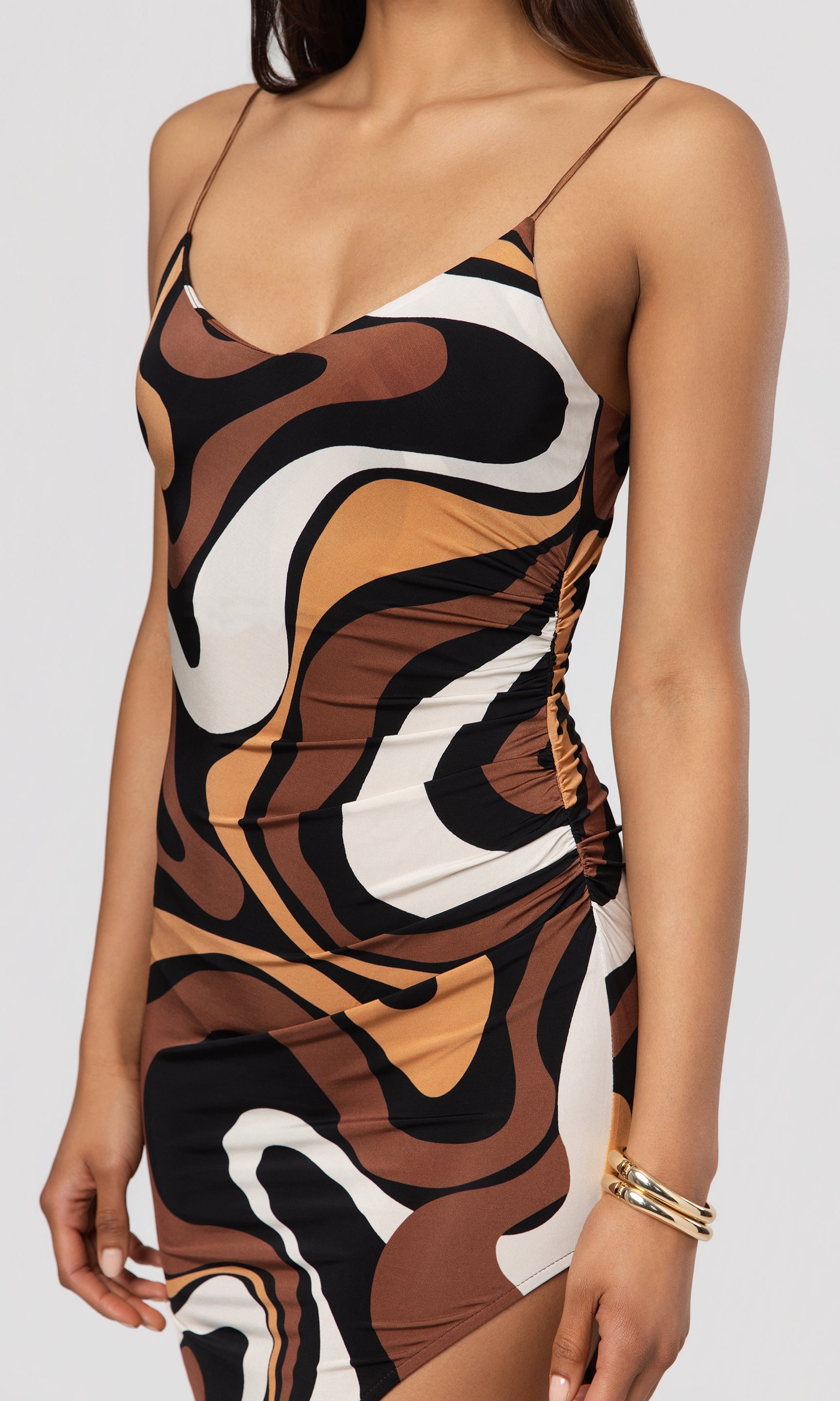 Close-up of woman wearing a patterned dress with brown, white, and black design on a plain background