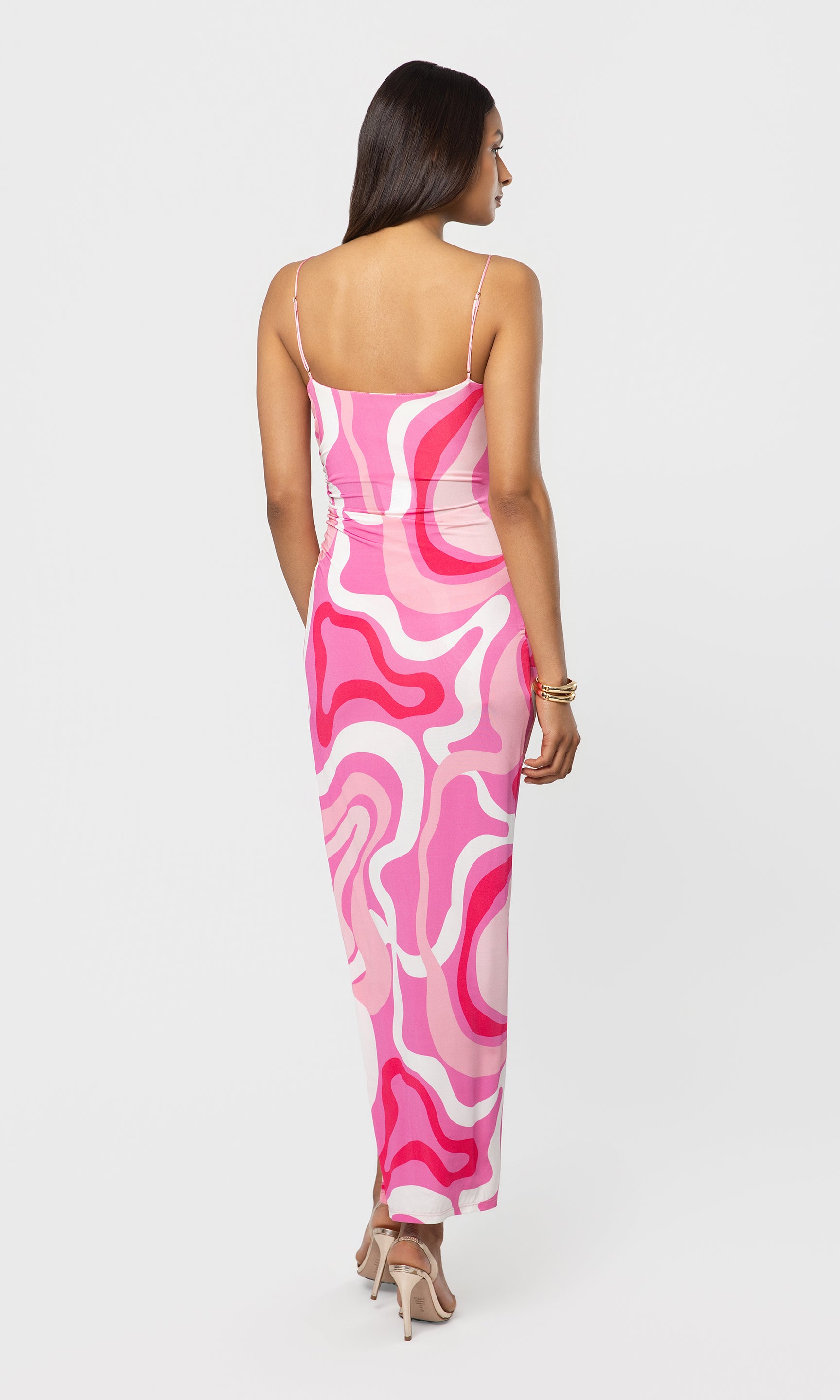 Back view of woman wearing a pink and white patterned dress on a white background