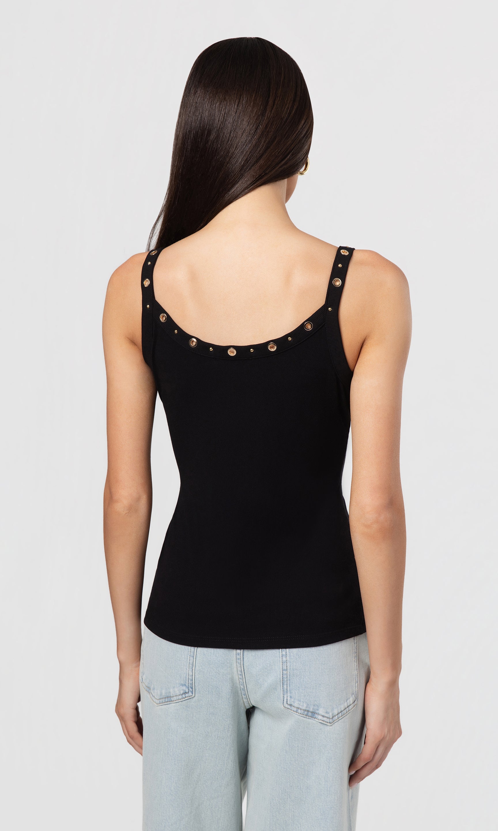 Back view of woman wearing a black tank top with decorative neckline on a plain background
