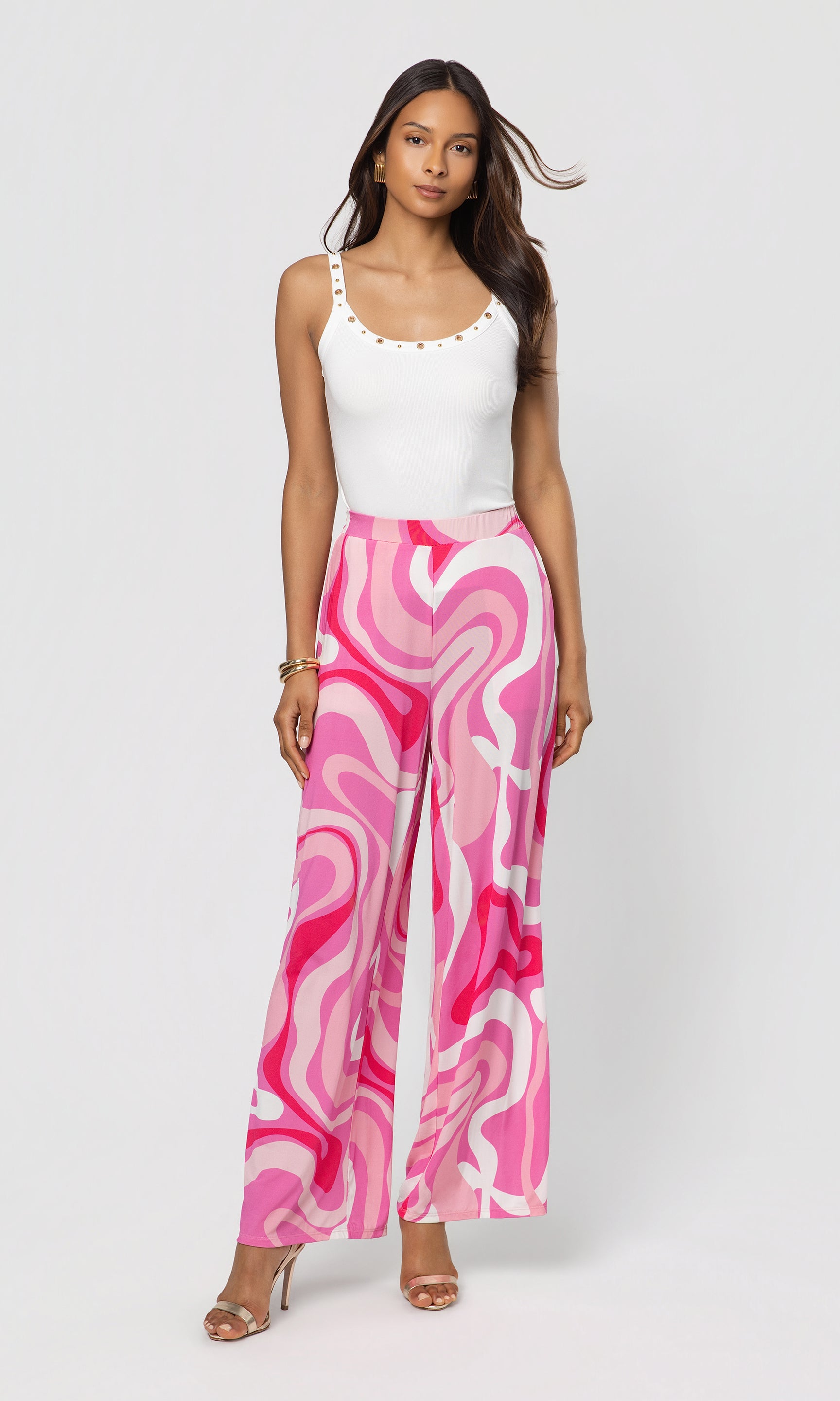 Woman wearing a white top and pink marbled pants on a white background