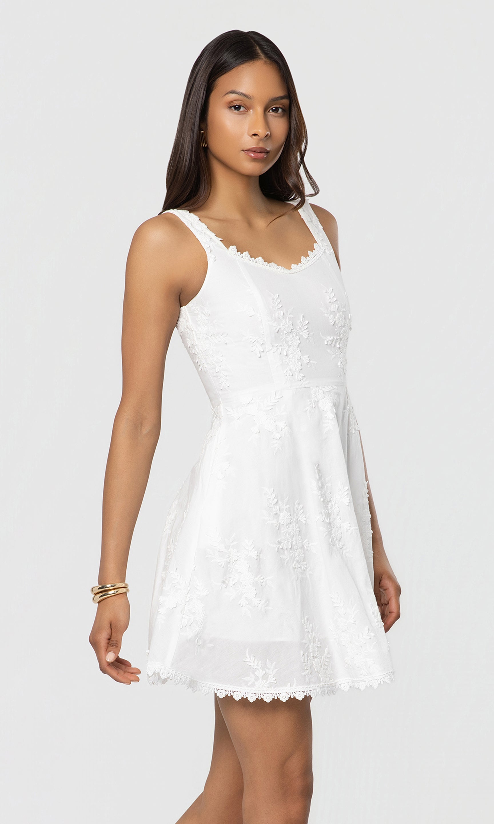 Side view of woman wearing a white lace dress against a plain background
