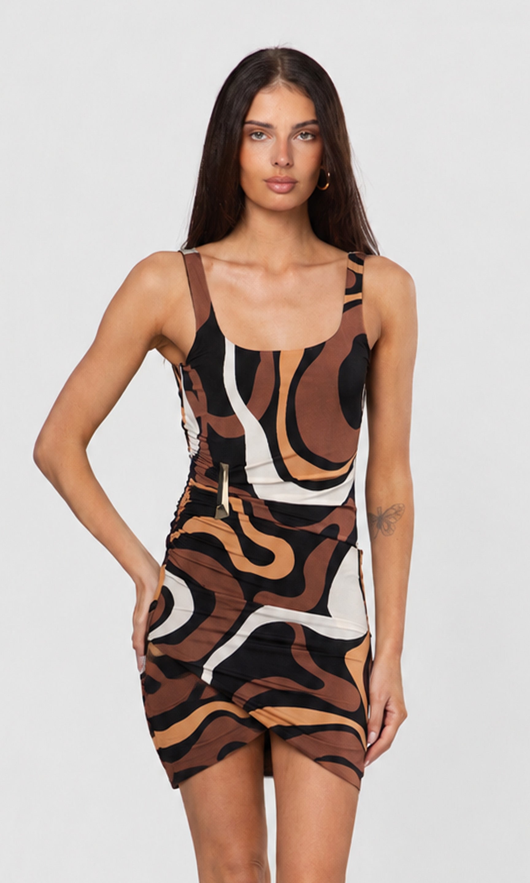 Woman wearing a brown patterned dress on a plain background