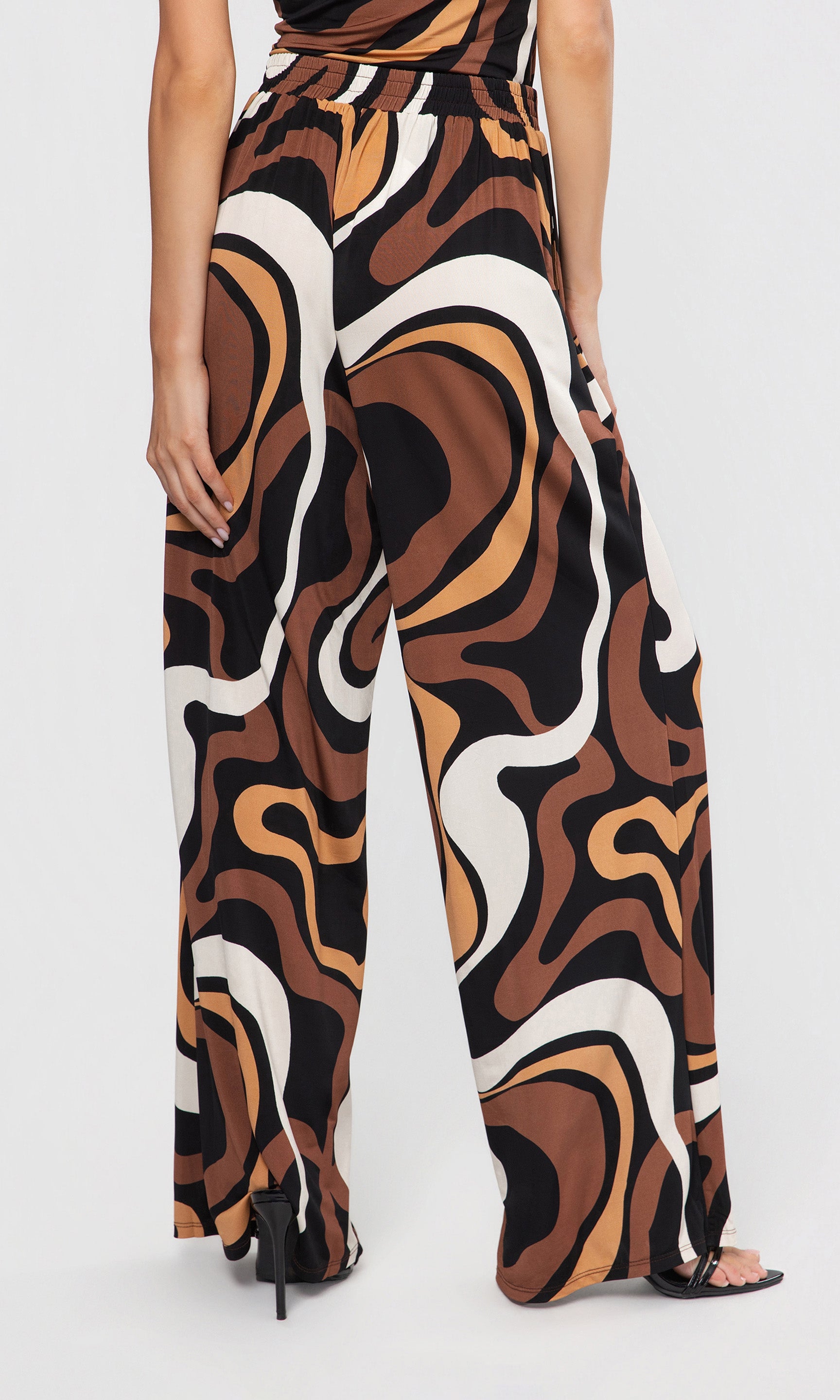 Back view of patterned pants with brown, black, and white design on a plain background