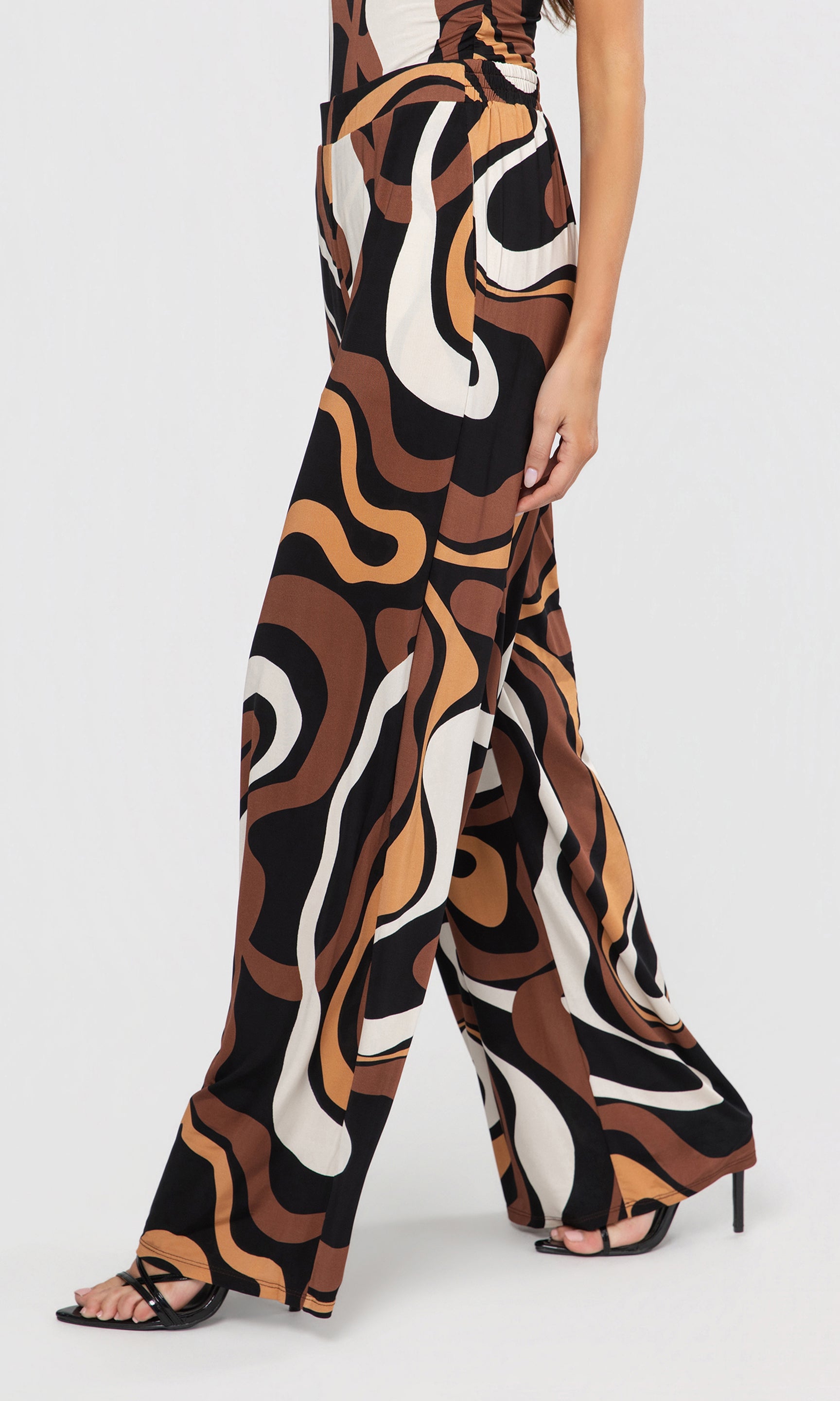 Side view of patterned pants worn by a person on a white background