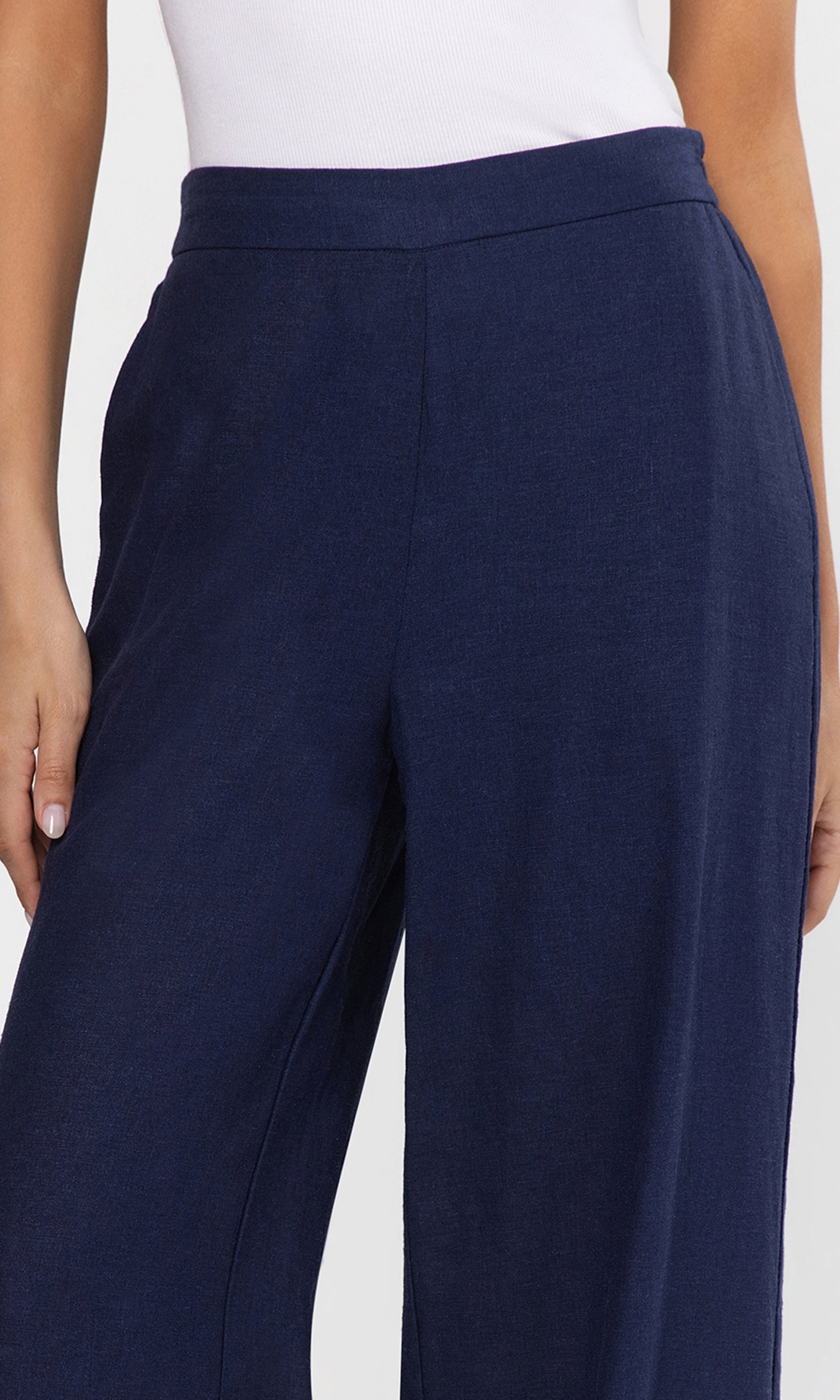 Close-up of navy blue pants worn by a person on a light gray background