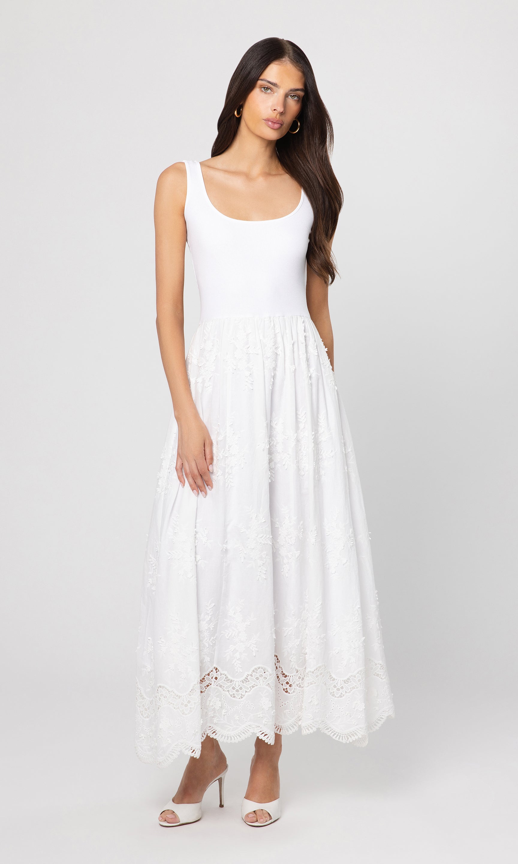 Woman wearing a white sleeveless dress with lace details on a white background