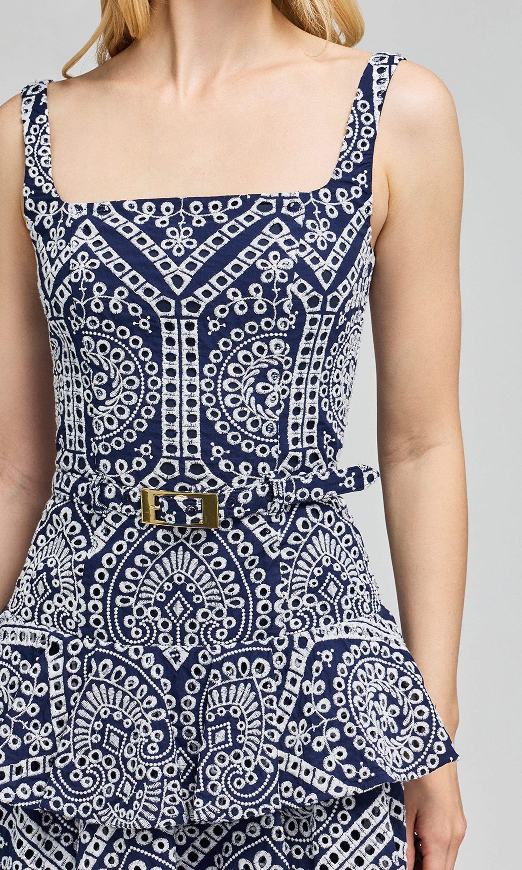 Close-up of navy and white patterned dress with a belt on a neutral background