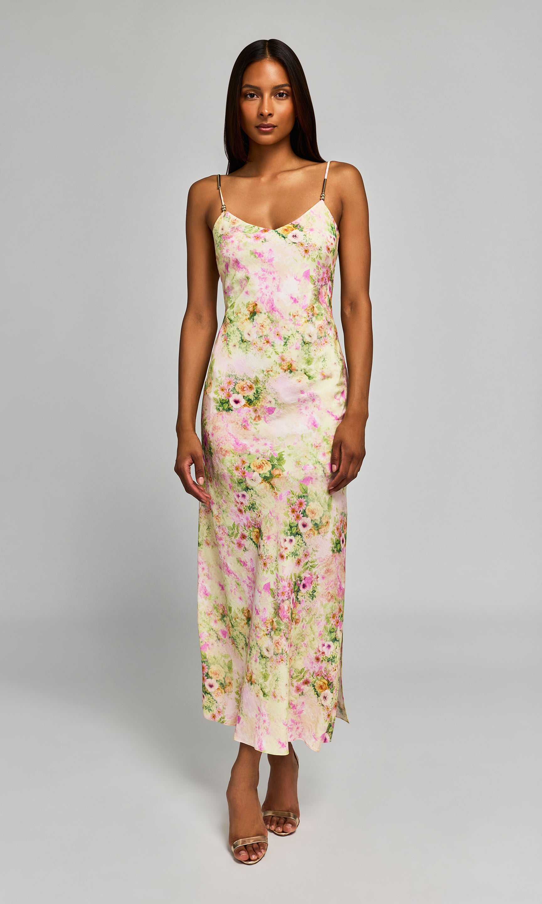 Woman wearing a pastel floral slip dress on a plain background.