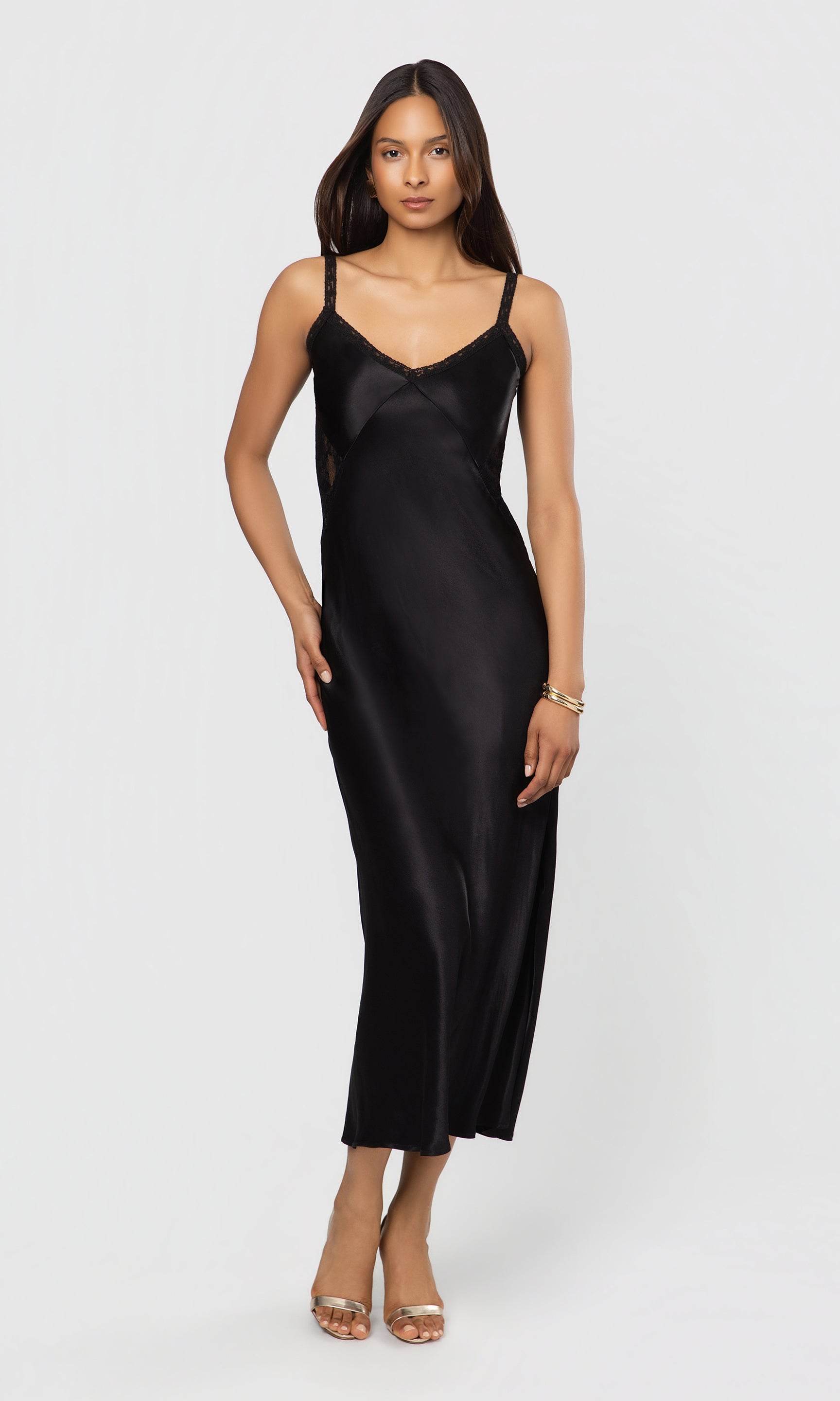 Woman wearing a black satin slip dress on a white background