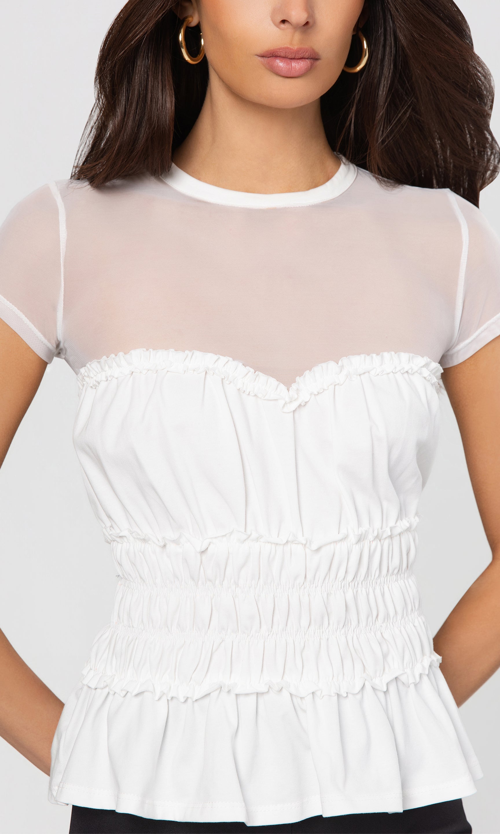 Close-up of white blouse with sheer sleeves worn by a model on a plain background