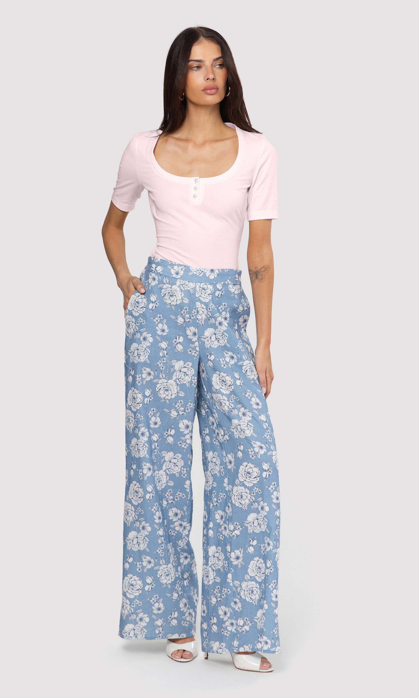 Woman wearing a pink top and blue floral pants on a white background
