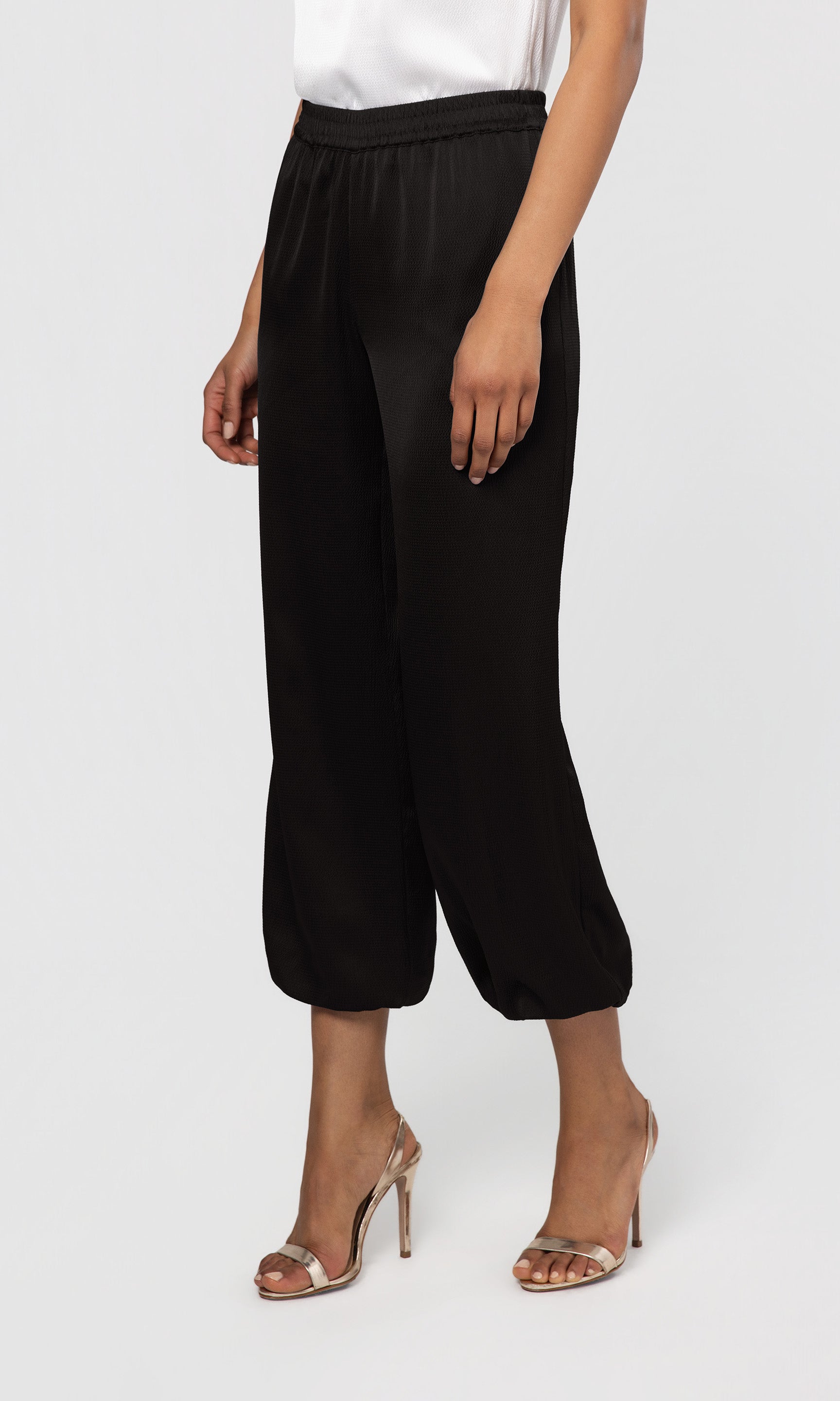Side view of person wearing black wide-leg pants on a white background