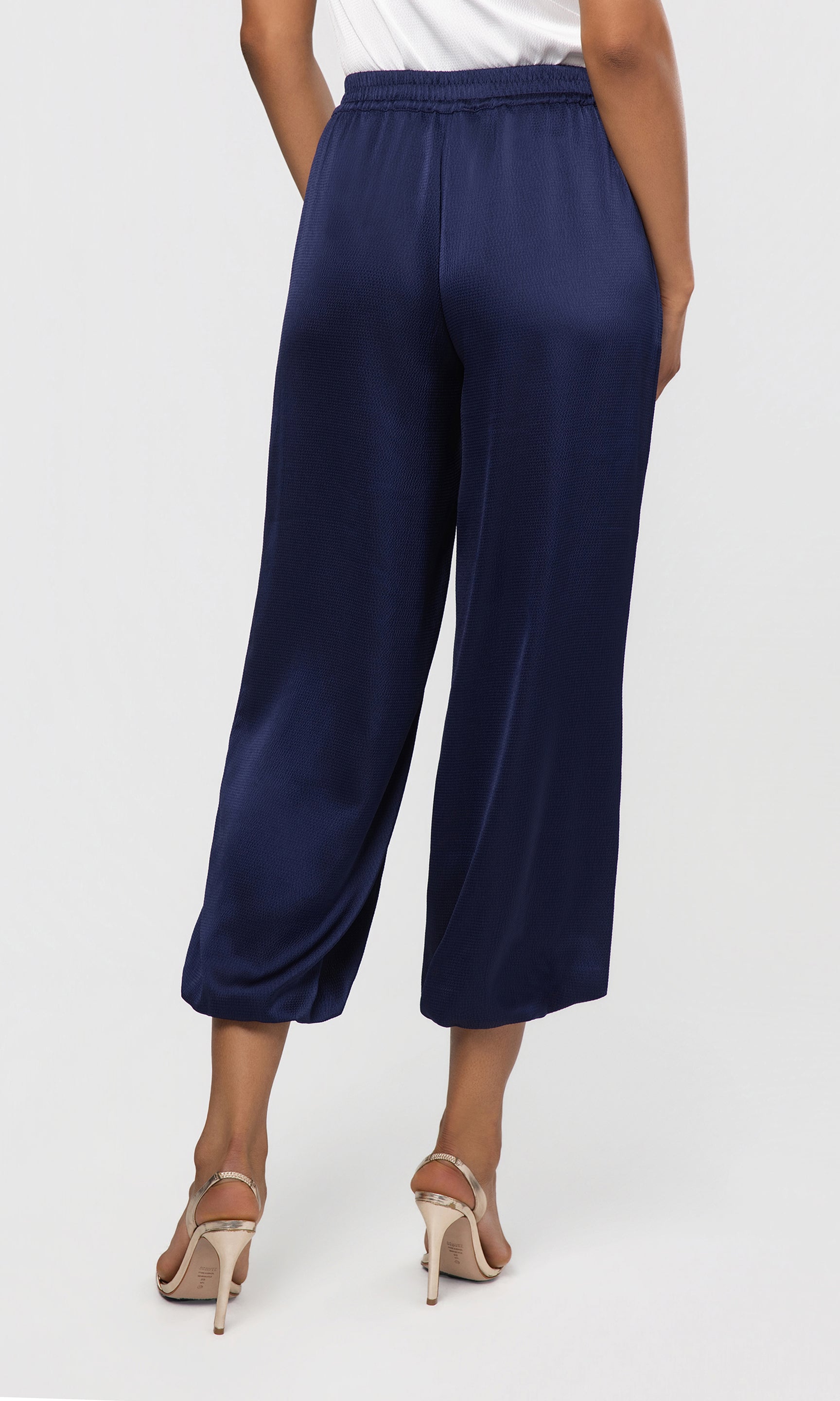 Back view of navy blue wide-leg pants worn by a person on a white background