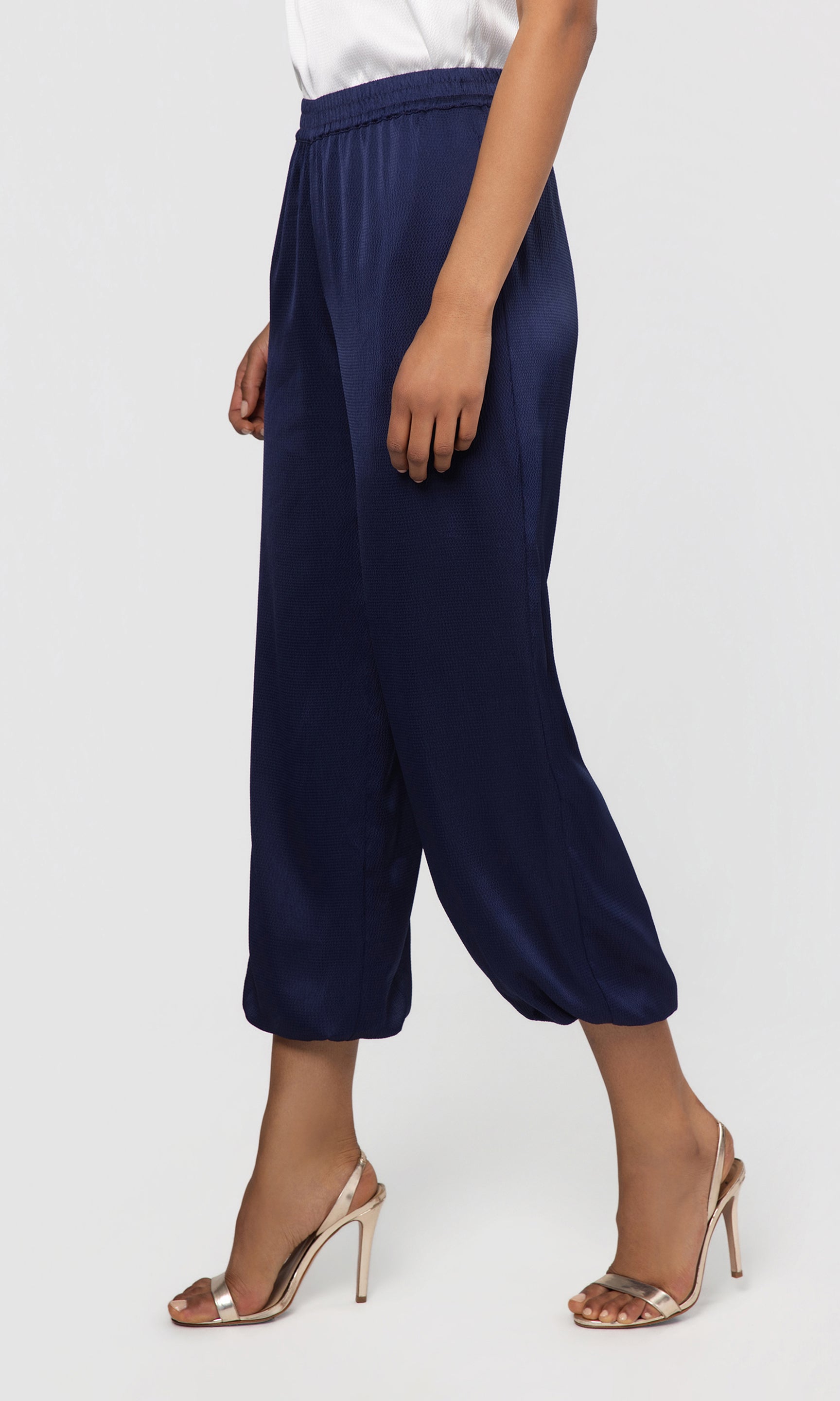 Side view of navy blue pants worn by a person on a white background