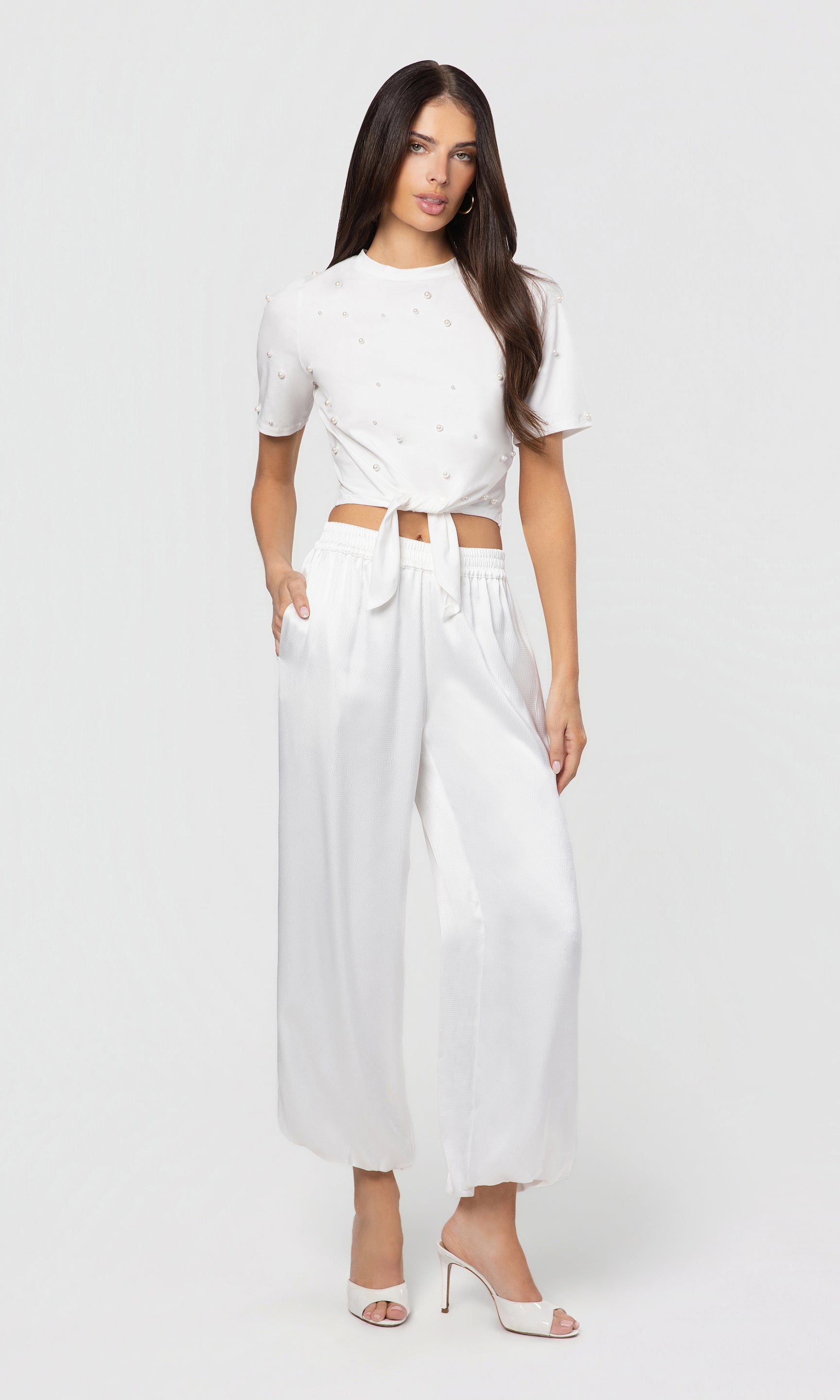 Woman wearing a white outfit with balloon pants on a white background
