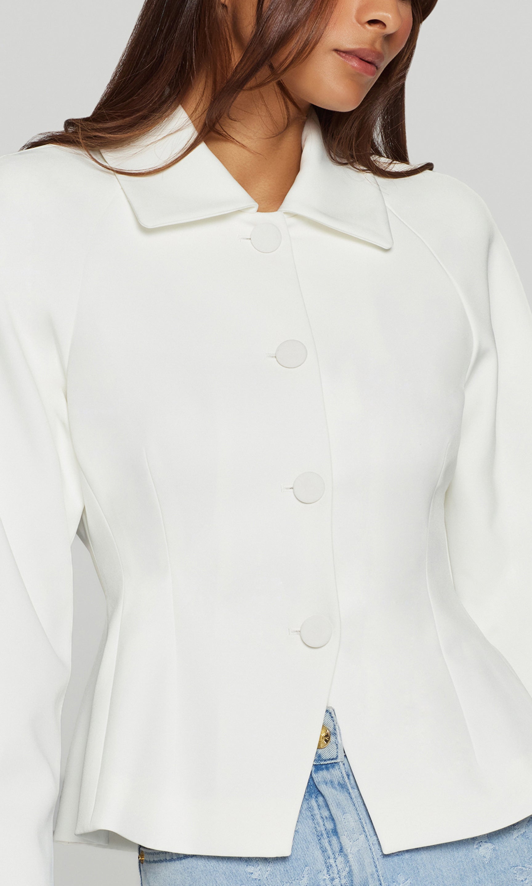Close-up of white jacket worn by a person with a neutral background