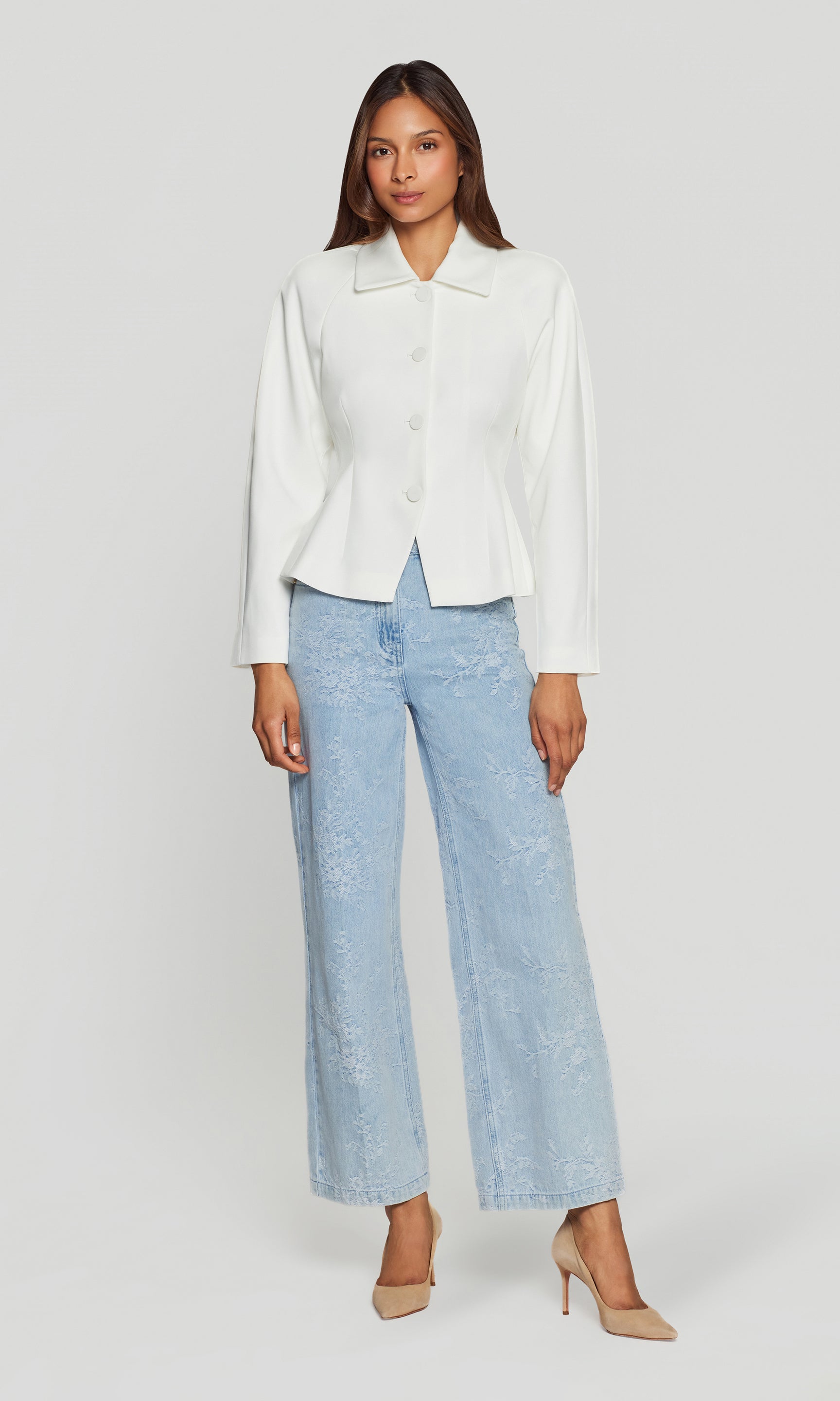 Woman wearing a white blazer and light blue jeans on a white background