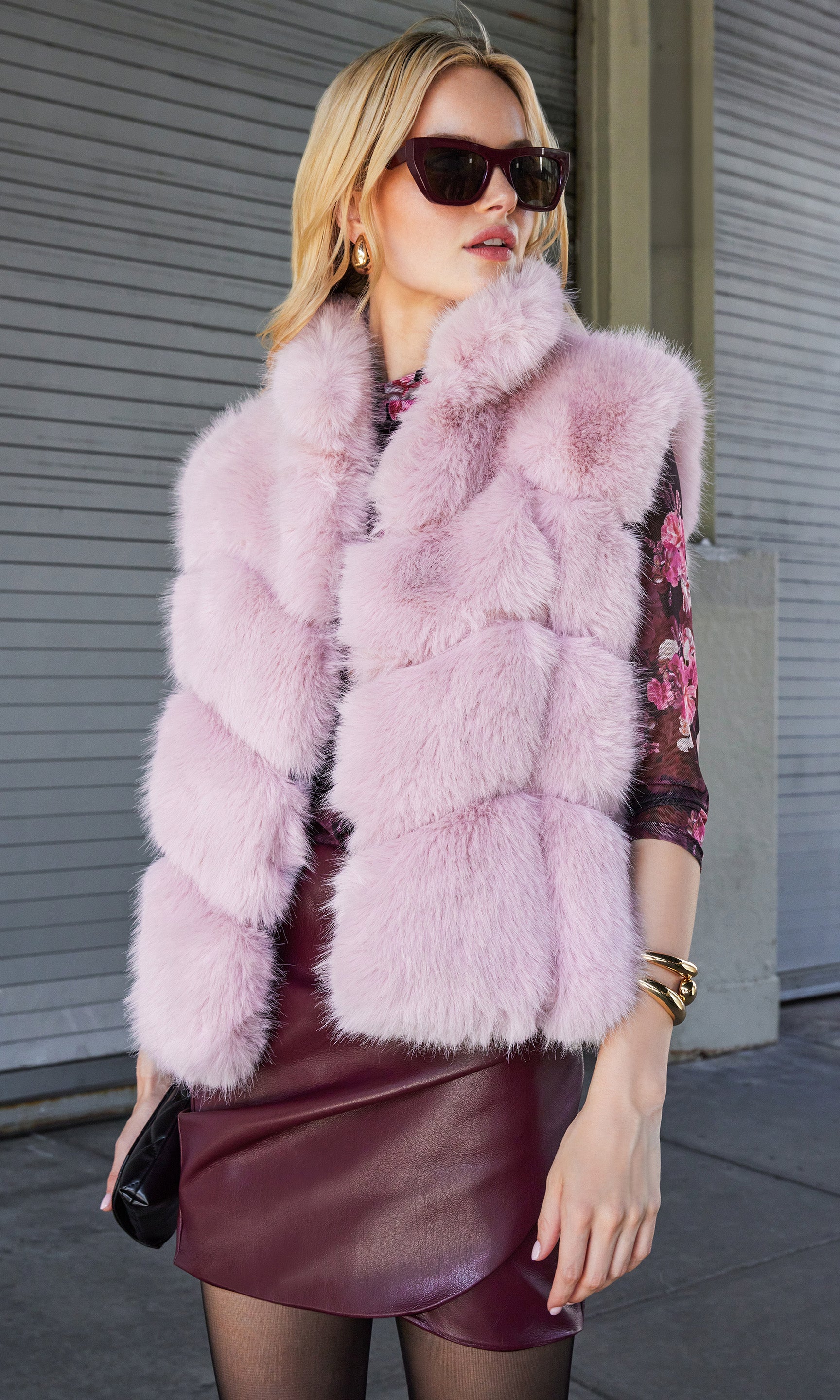 Side walking view of Rosario Faux Fur Vest in blush pink, adding a chic layer to a floral blouse and skirt outfit.
