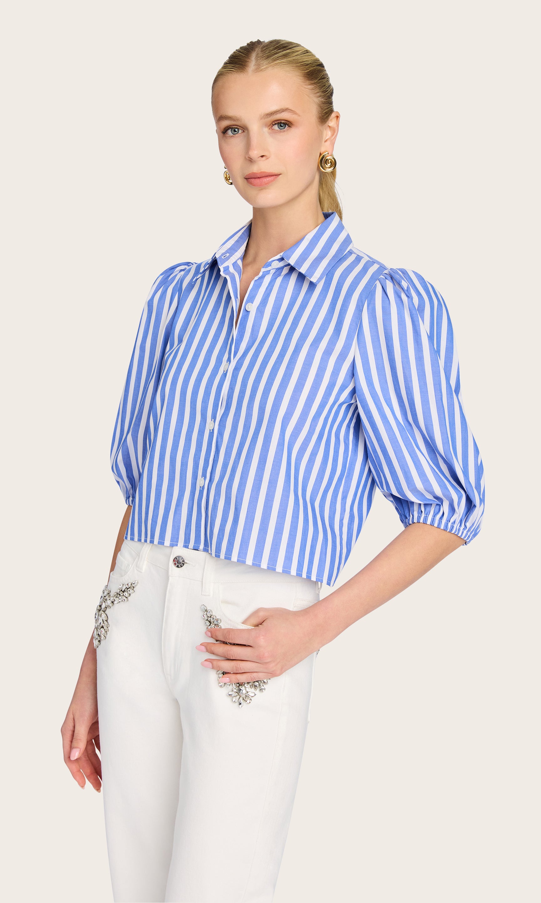 3/4 front view of model wearing the Tammy Wide Stripe Shirt in blue/white, styled effortlessly with high-waisted white pants.