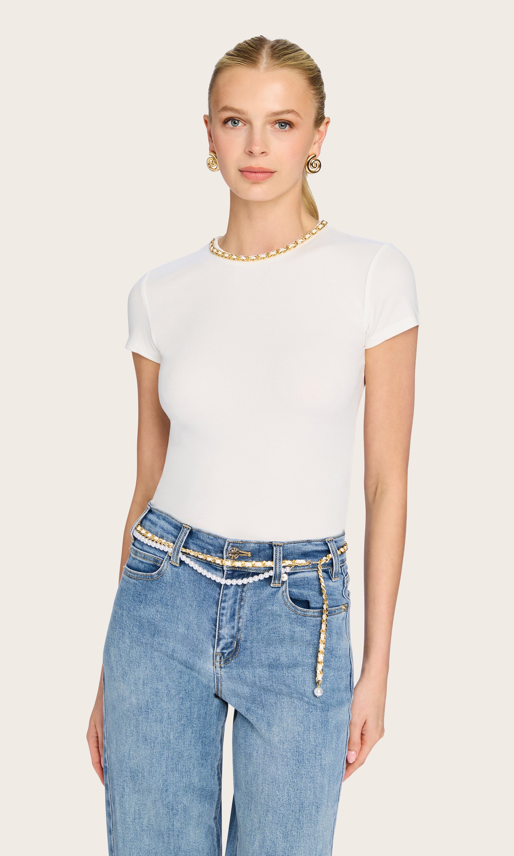 front image of model wearing the Tate t-shirt in white with a chain detail on the neckline, paired with blue jeans