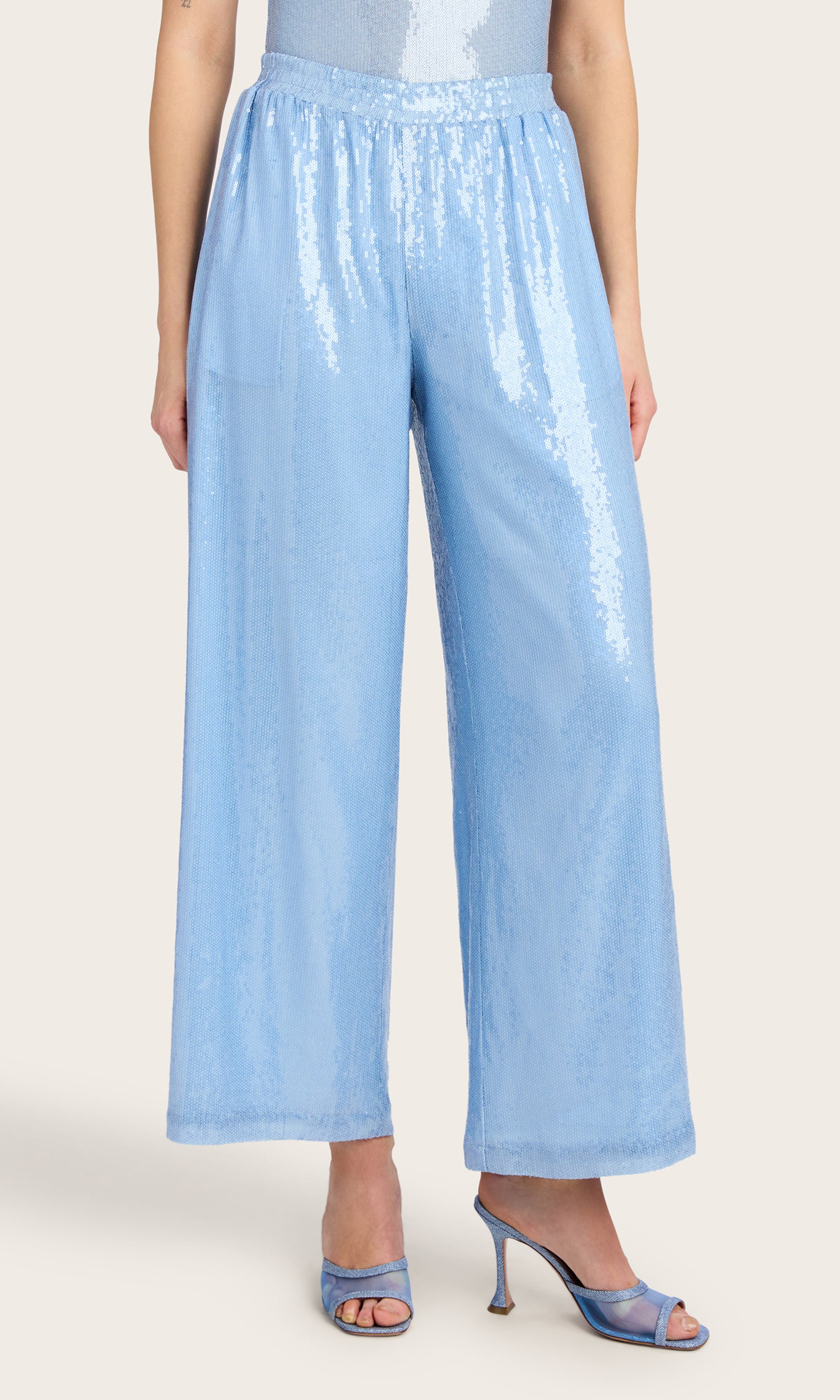 3/4 Front view image of the model wearing the Talia Sequin Pants in light blue, styled with a matching sleeveless bodysuit and heels.