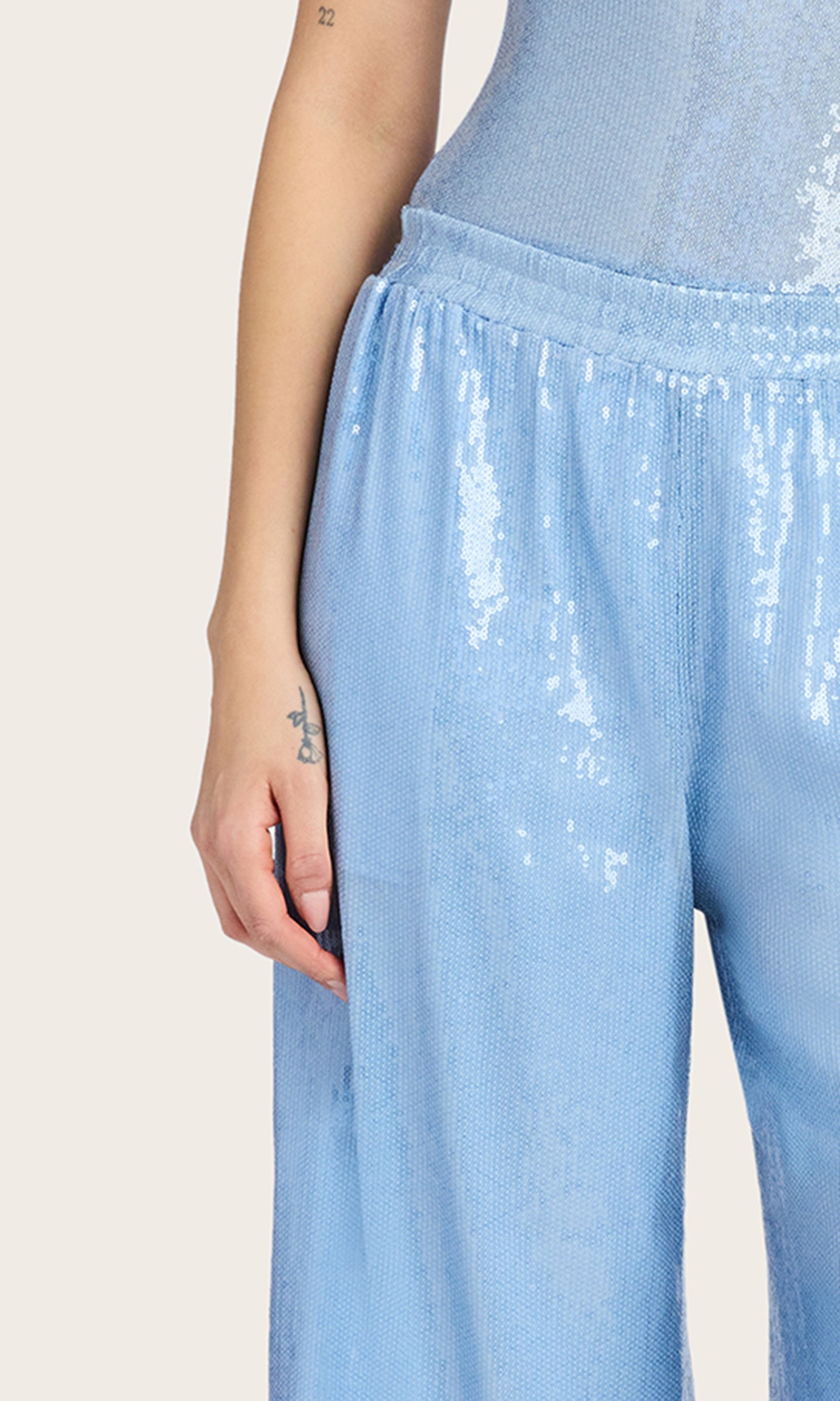 Zoomed in detail of sequins image of the model wearing the Talia Sequin Pants in light blue, styled with a matching sleeveless bodysuit.