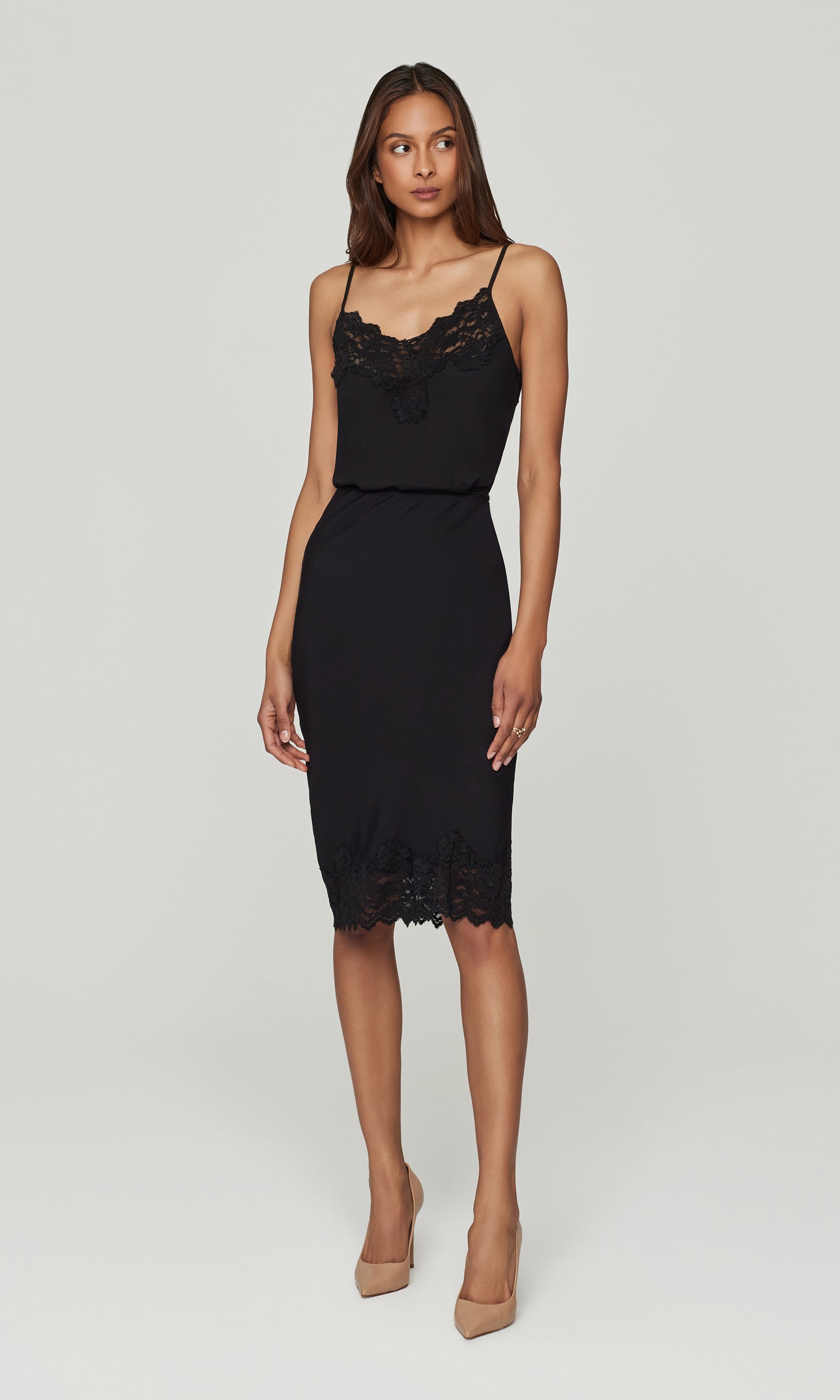 Woman wearing a black lace cami and skirt with with lace details on a white background