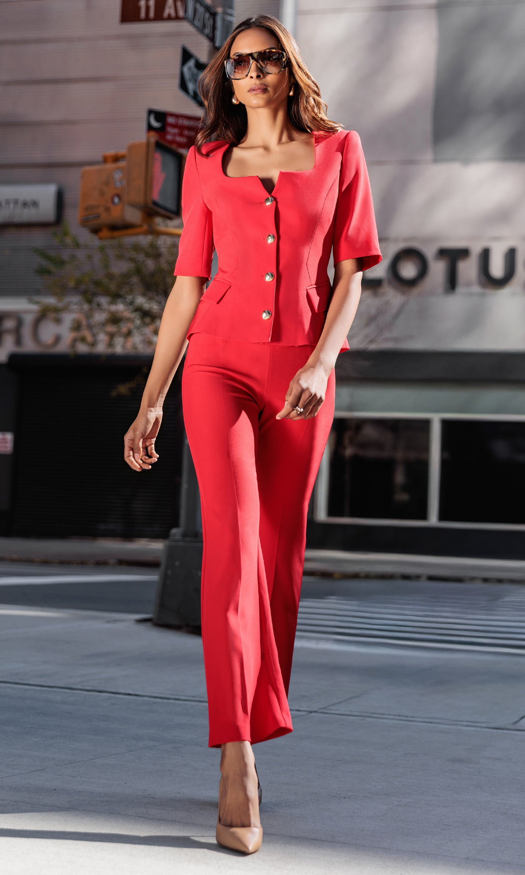 Woman in a red outfit walking on a city street.