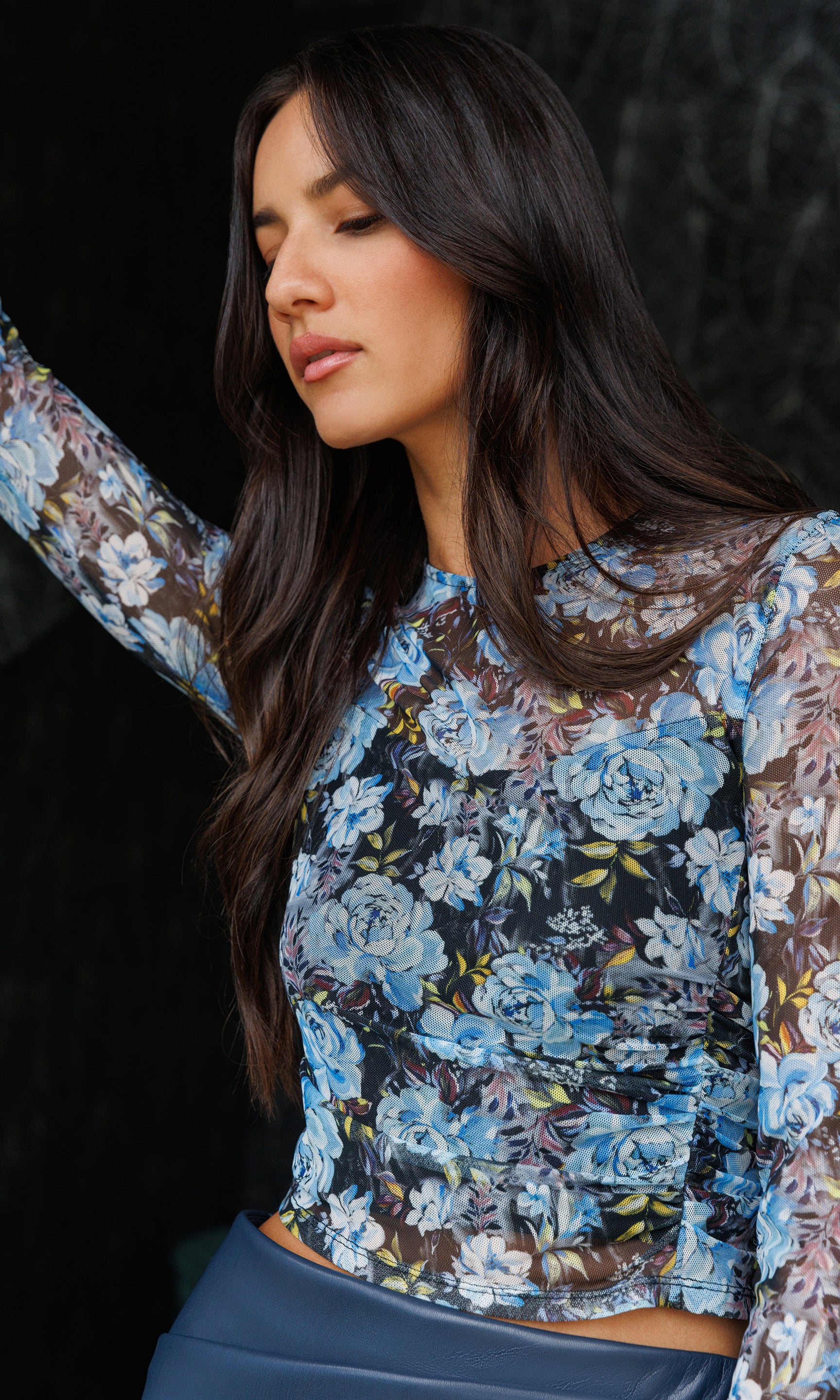 Close-up of woman wearing a floral blouse with a dark background